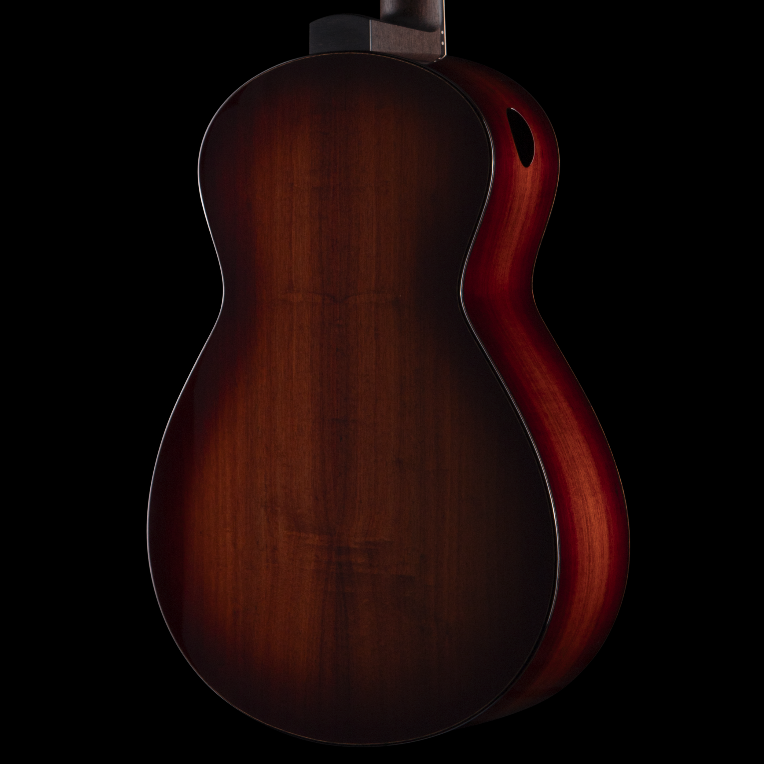 Close-up of a mahogany wooden Dion guitar body against a black background.
