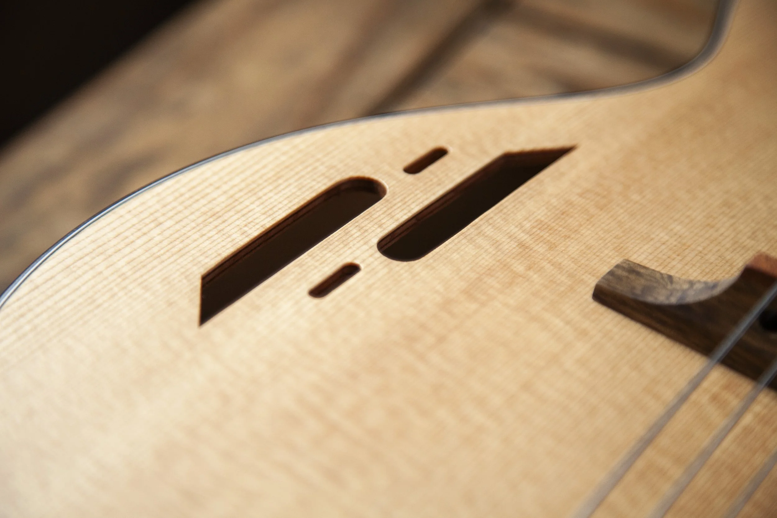 Close-up of a wooden acoustic Island Instruments guitar with sound hole and internal bracing visible.