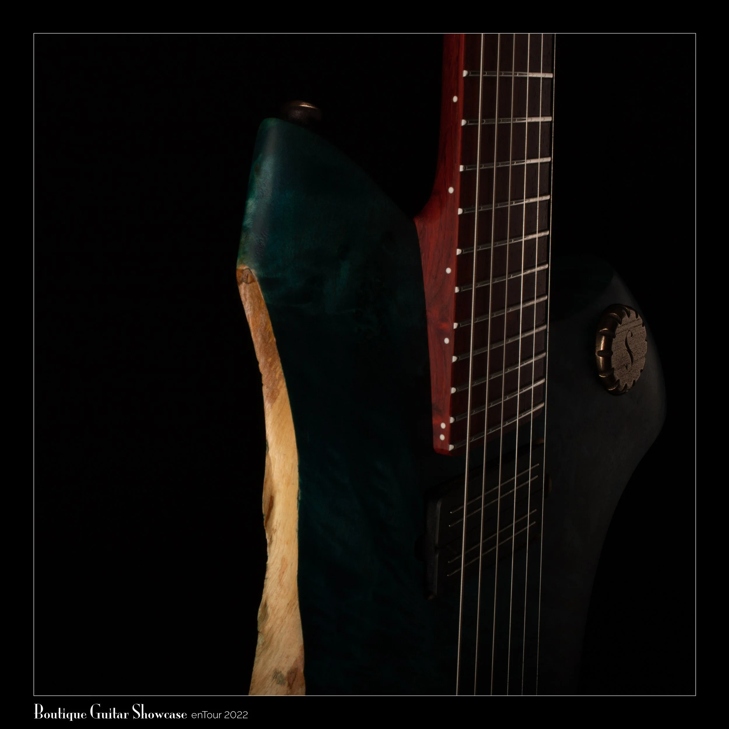 Close-up of a Sankey custom electric guitar with a unique wood grain design and artistic finish, showcasing the neck, frets, and a knob, partly illuminated against a dark background.