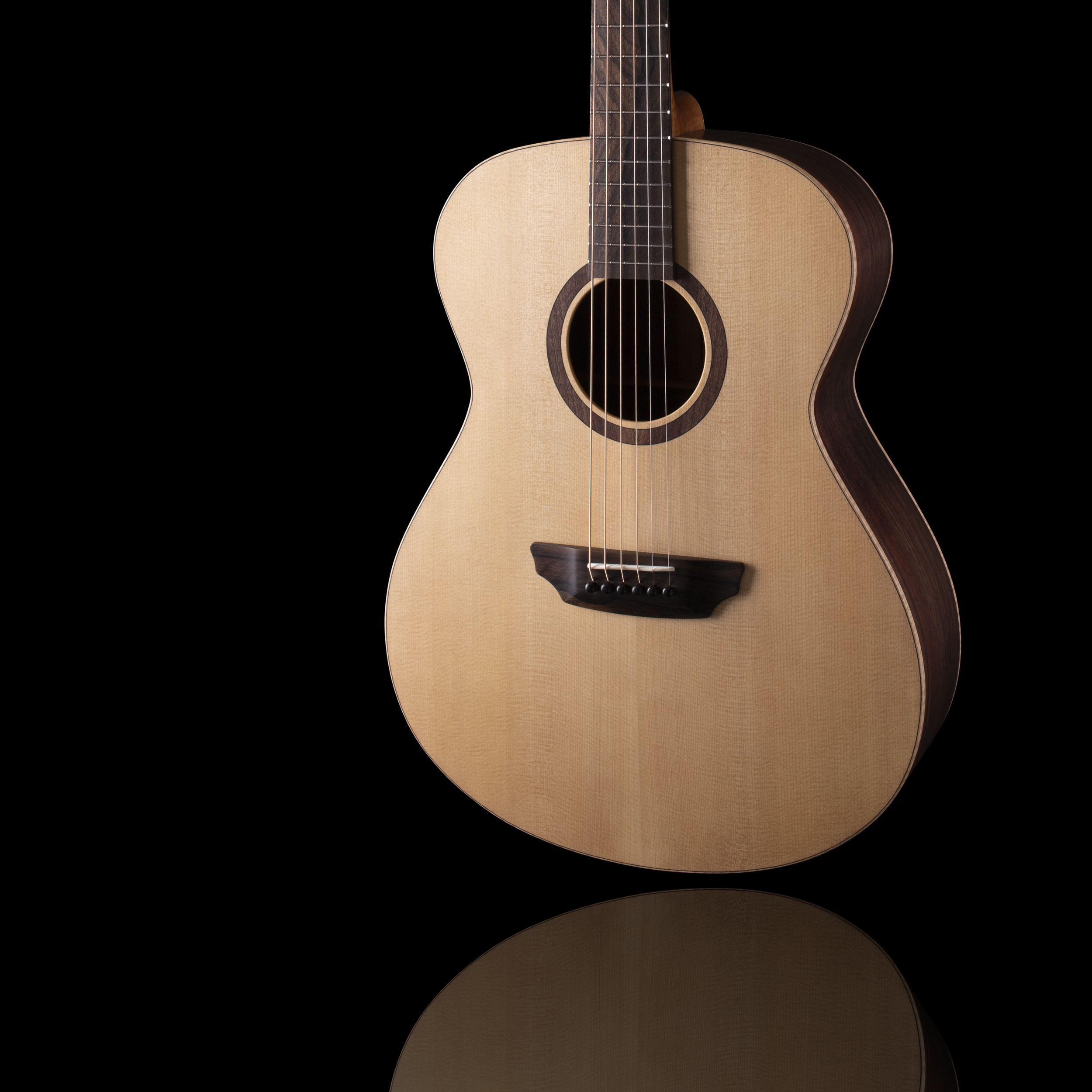 Close-up of a Donovan Leah acoustic Caroline guitar against a black background, showing the body, sound hole, and part of the fretboard.