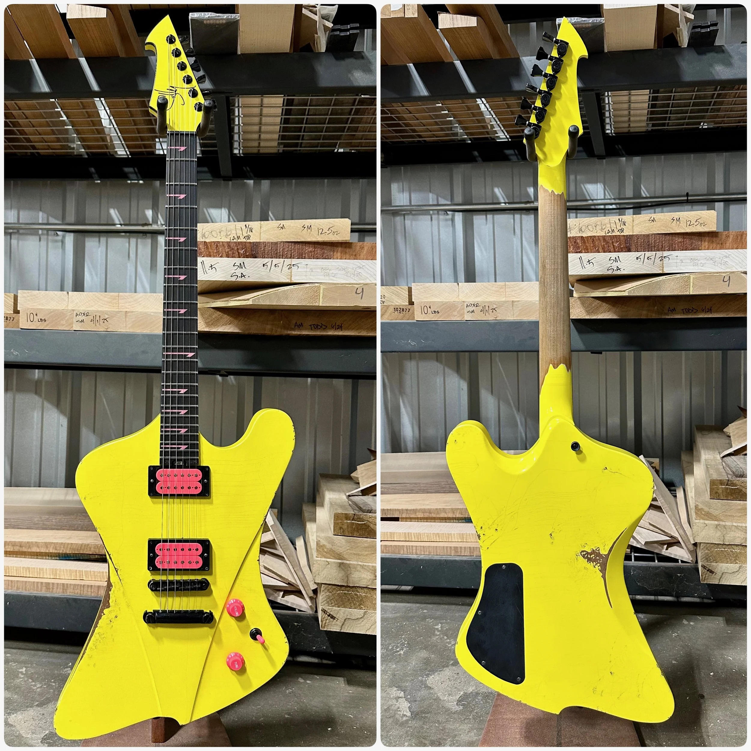 A yellow Sully electric guitar with an angular body shape, black pickups, and pink knobs, displayed on a stand in a workshop. The back shows signs of wear and tear.