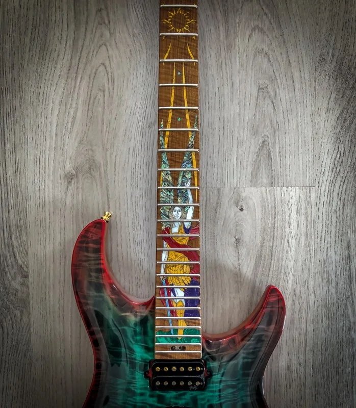 GNG Giulio Negrini Guitar with a colorful fretboard design featuring intricate artwork, placed on a wooden surface.