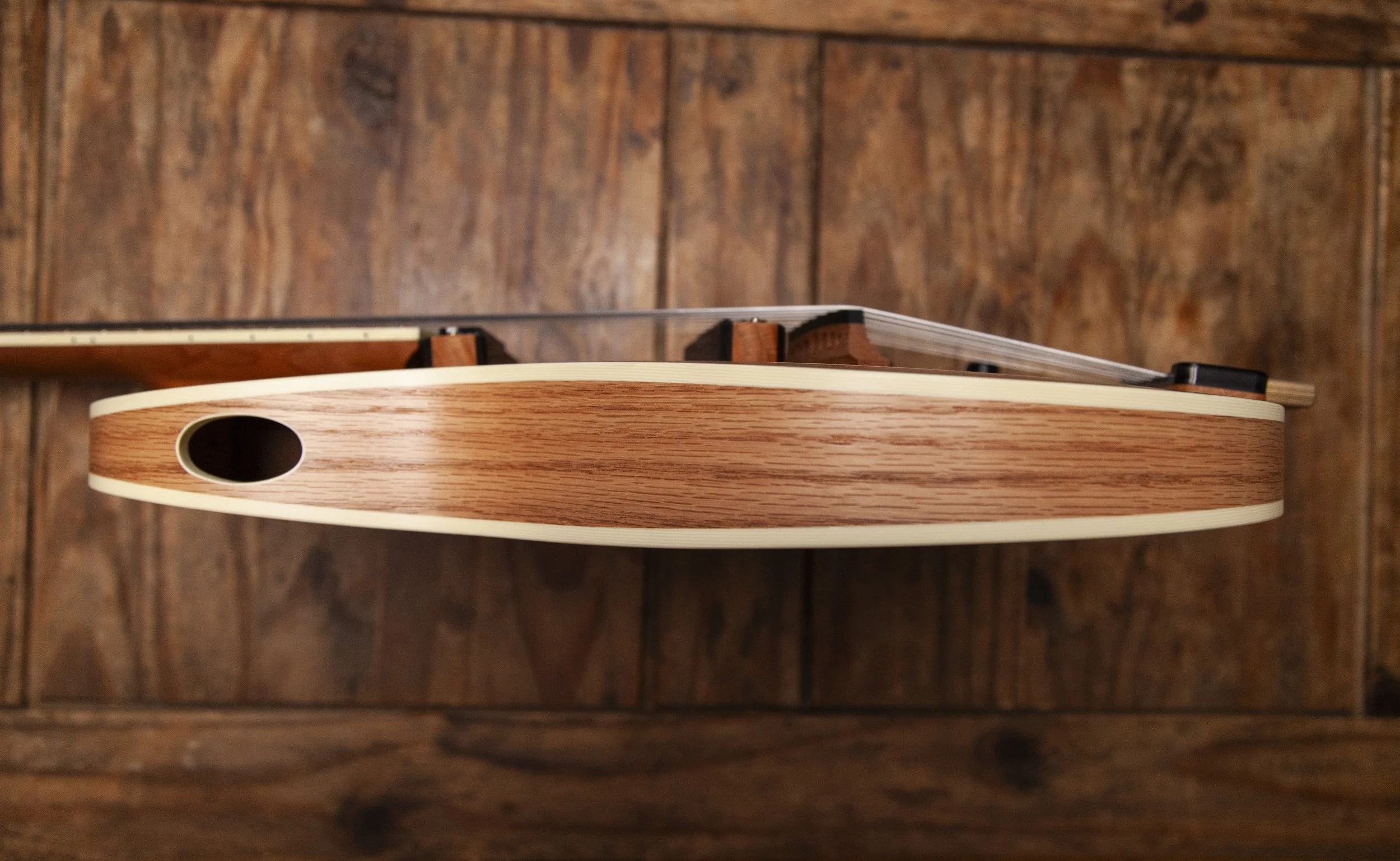 Side view of an Island Instruments acoustic guitar with a wooden background.