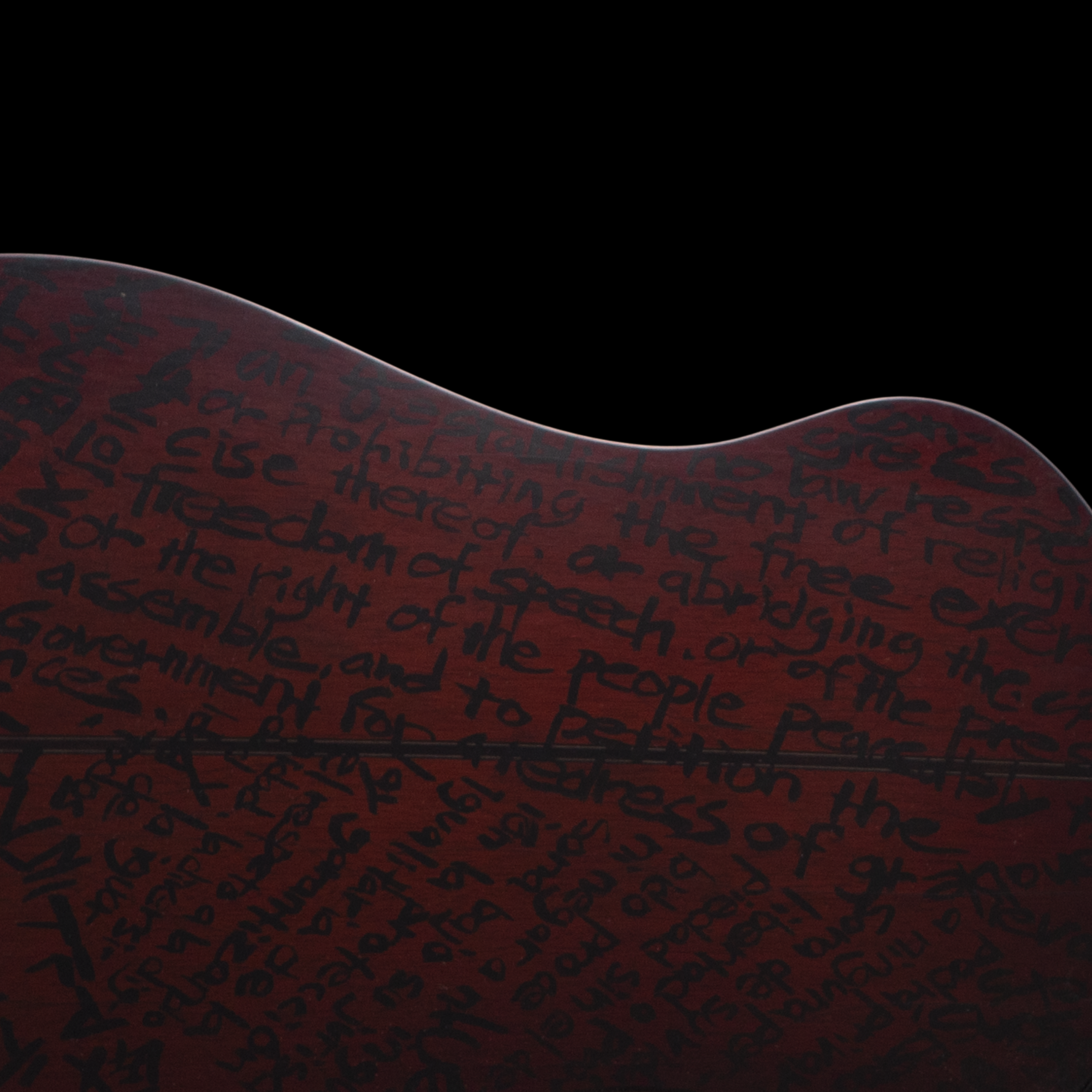A Matsuda guitar with a dark red body featuring handwritten text in black, viewed from the back against a black background.
