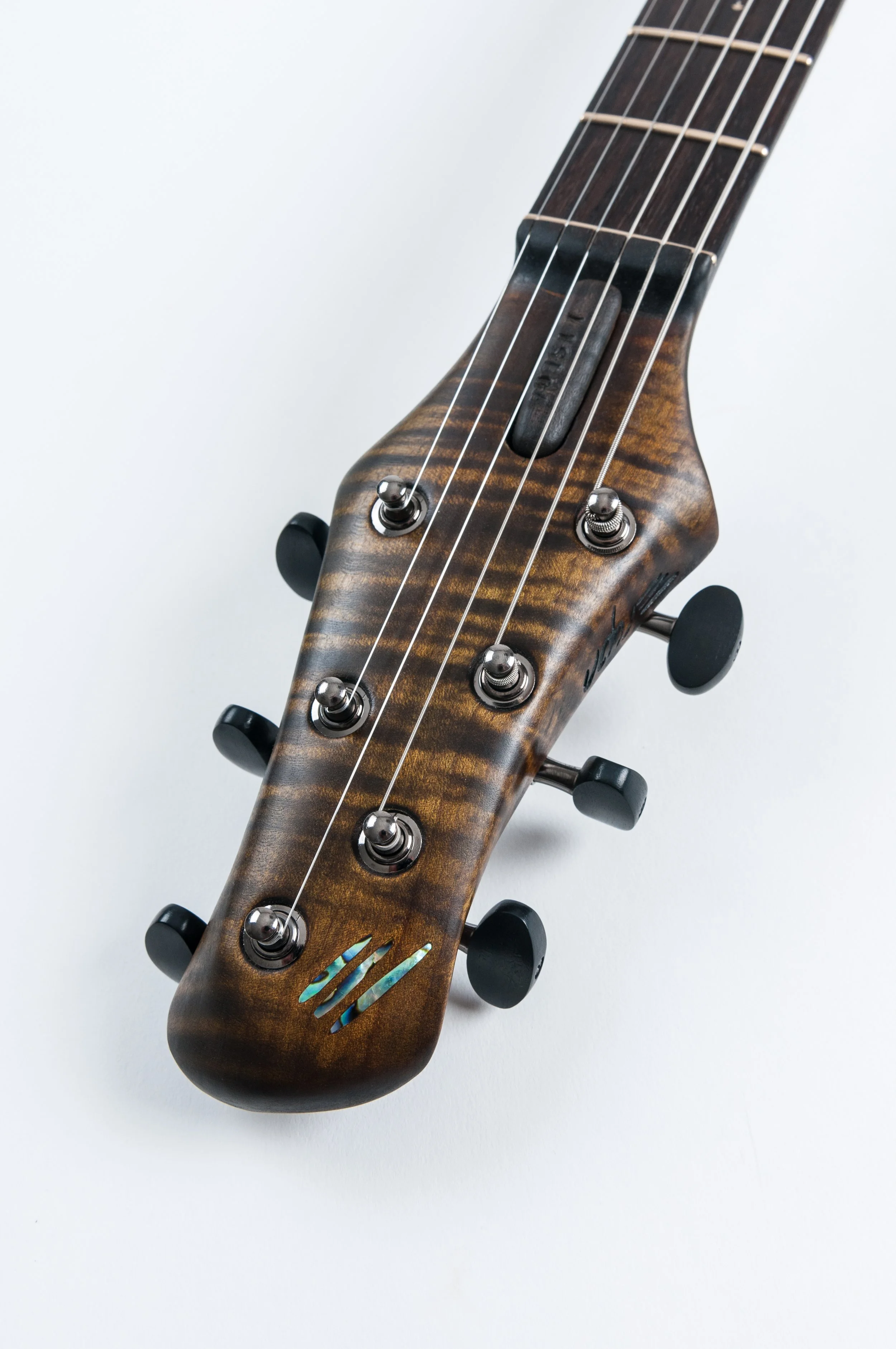 Close-up of an Ergon headstock of an electric guitar with tuning pegs and strings against a white background.