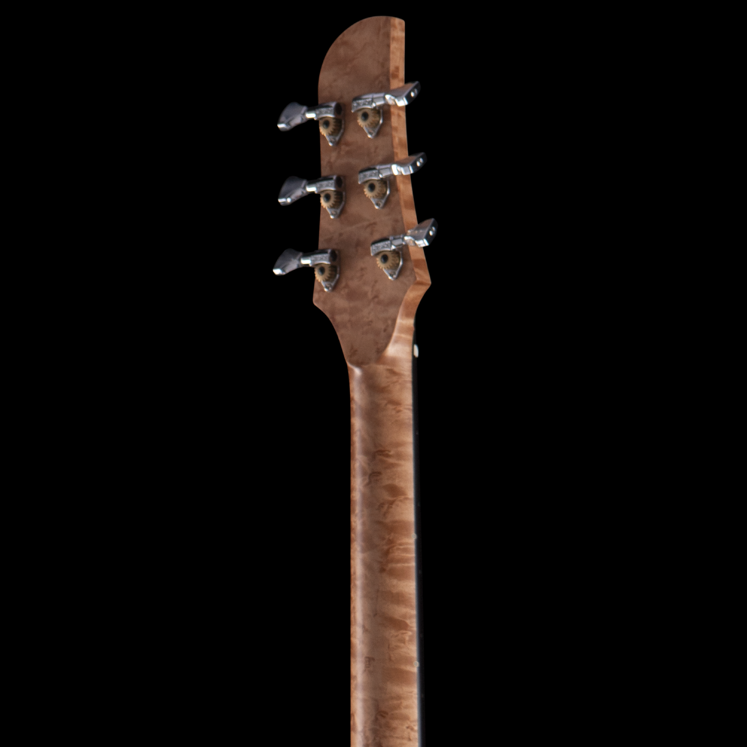 Close-up of the Bacci headstock of a wooden guitar showing tuning pegs and gears against a black background.