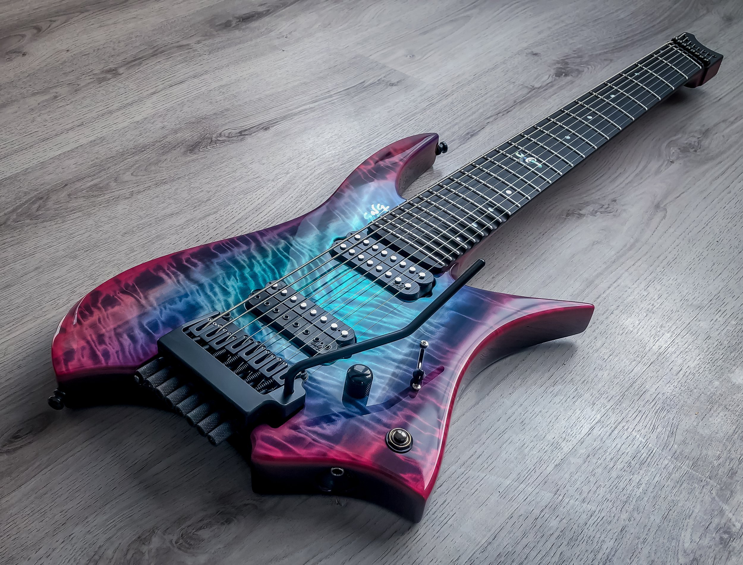 GNG Giulio Negrini electric guitar with a colorful, flame-like pattern finish, lying on a wooden floor.