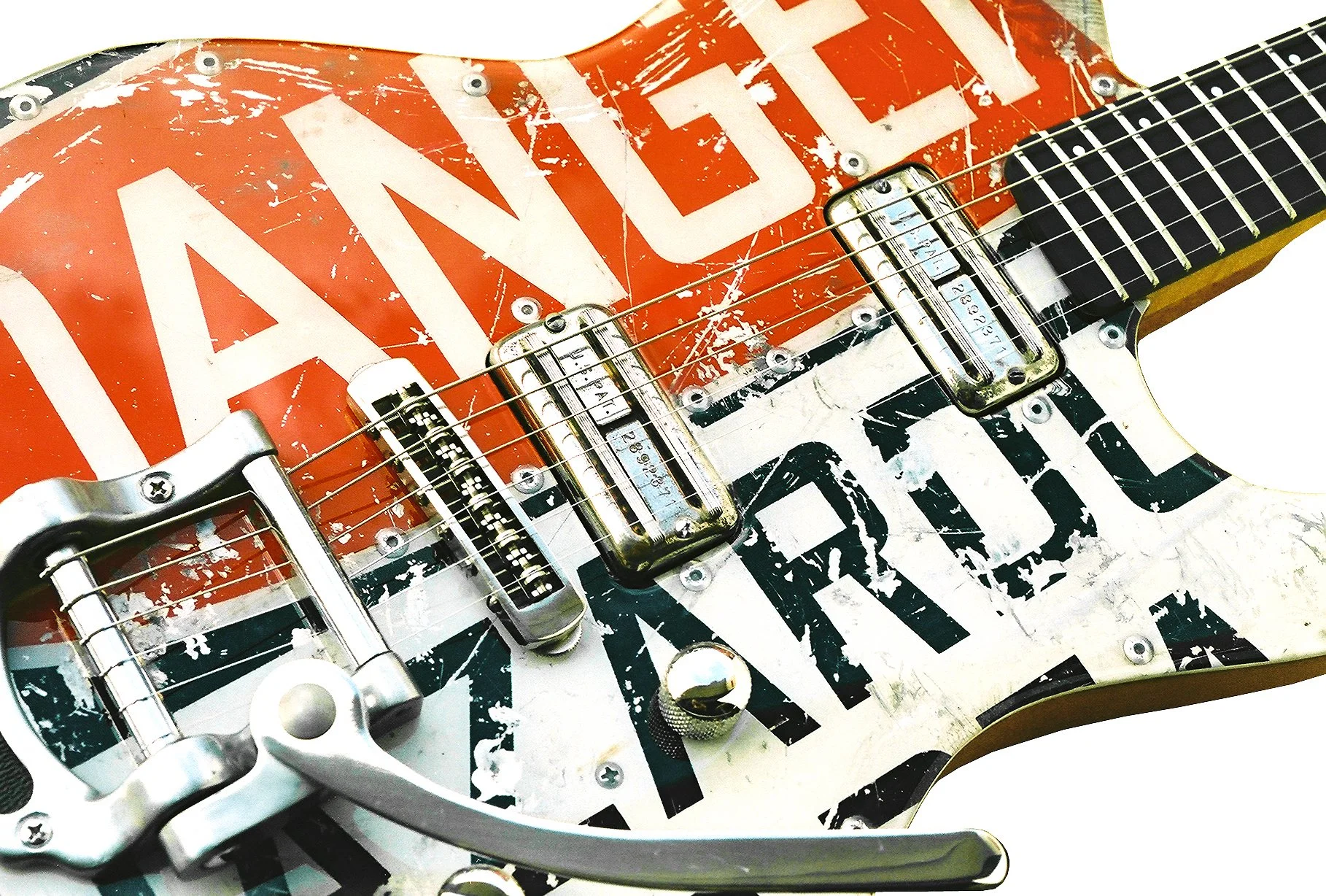 Close-up of a Spalt electric guitar with a vintage look and a red, white, and black painted design featuring overlapping text and graphics, with visible strings and hardware.