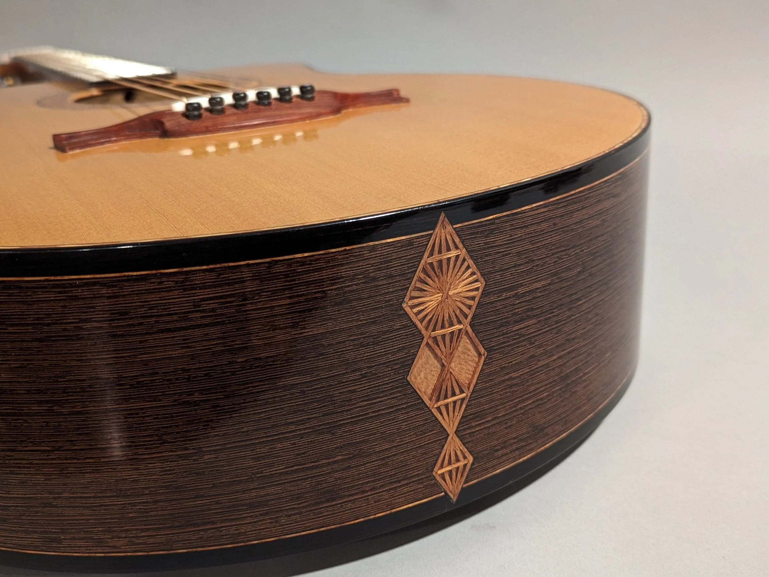 Close-up of a Morgan Kelsey acoustic guitar's body with a decorative geometric inlay on the side, showing wood grain and craftsmanship.