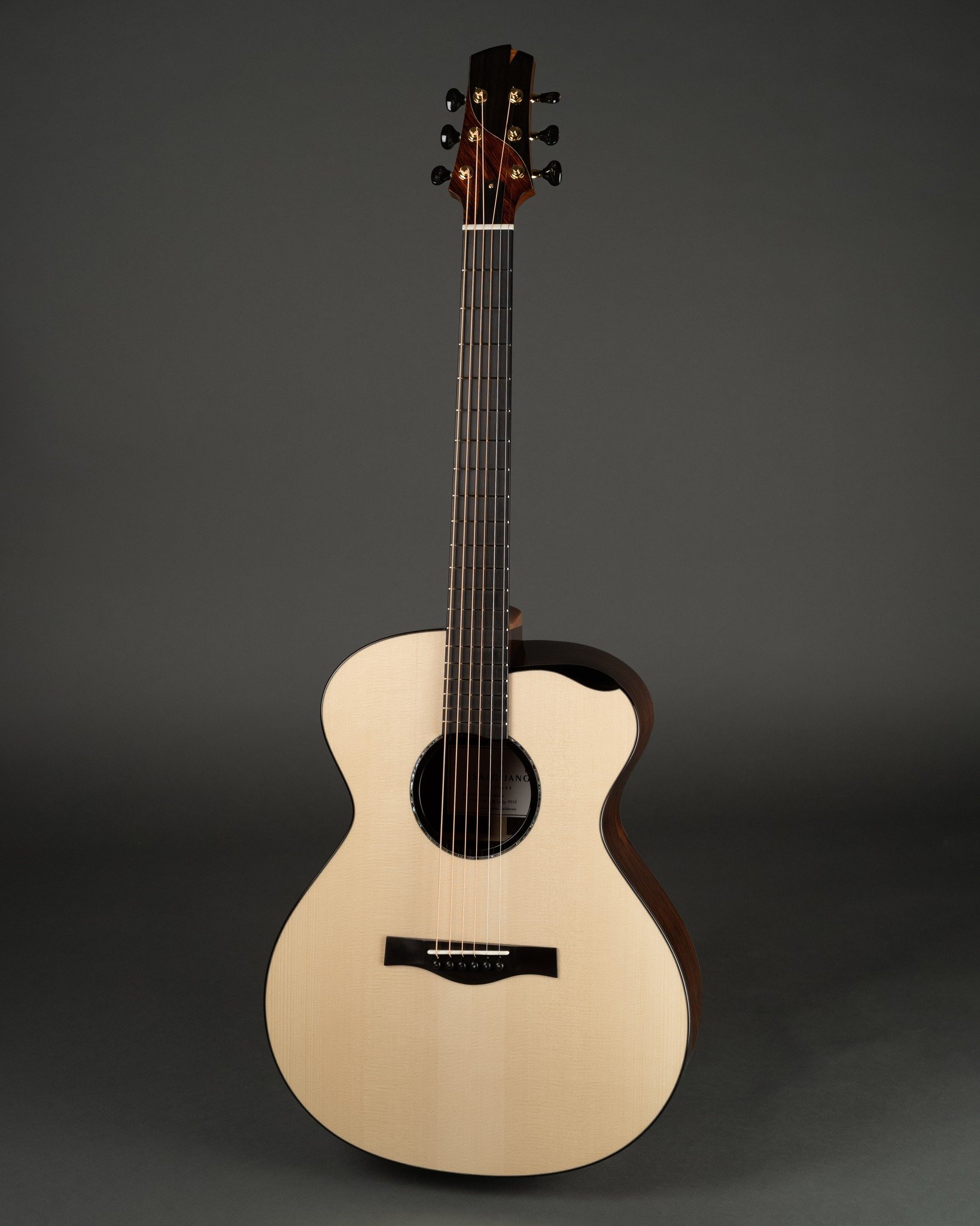 A light-colored acoustic Isaac Jang guitar with a dark neck and headstock, set against a dark background.