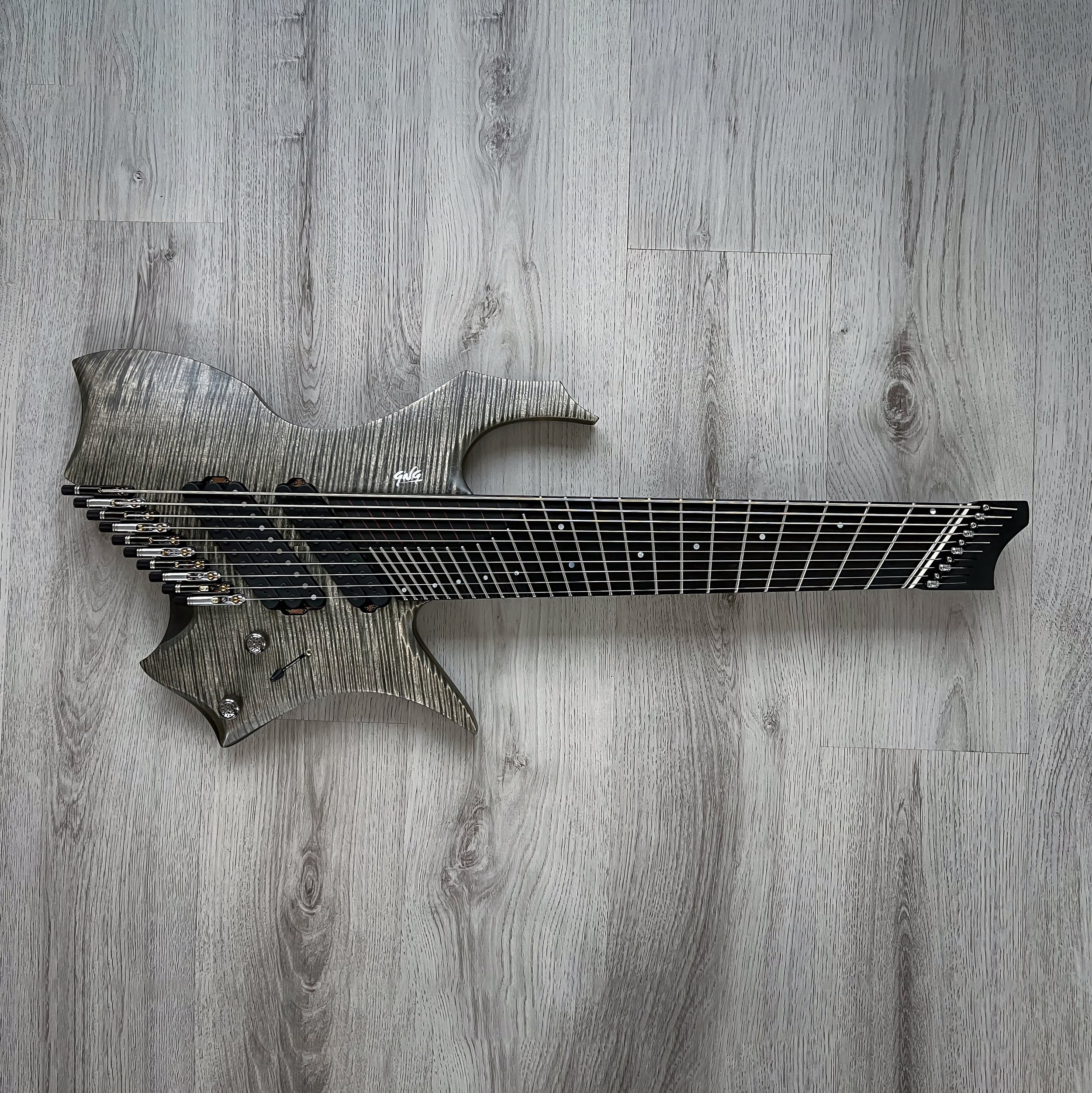 GNG Giulio Negrini electric guitar with a unique, futuristic design and a wood grain finish, lying on a light-colored wooden floor.
