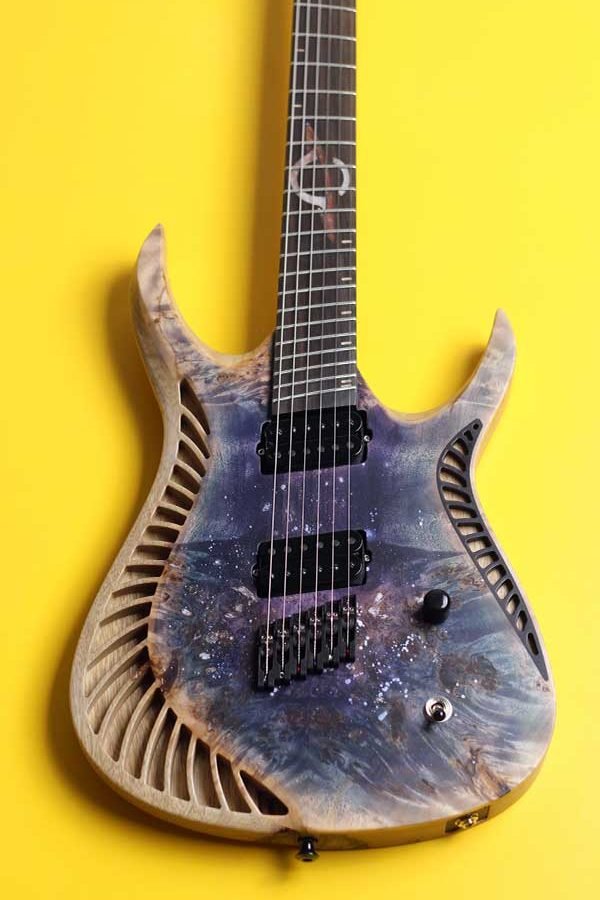 OD Guitars electric Venus model with a natural wood finish and a painted galaxy on the lower part, set against a yellow background.