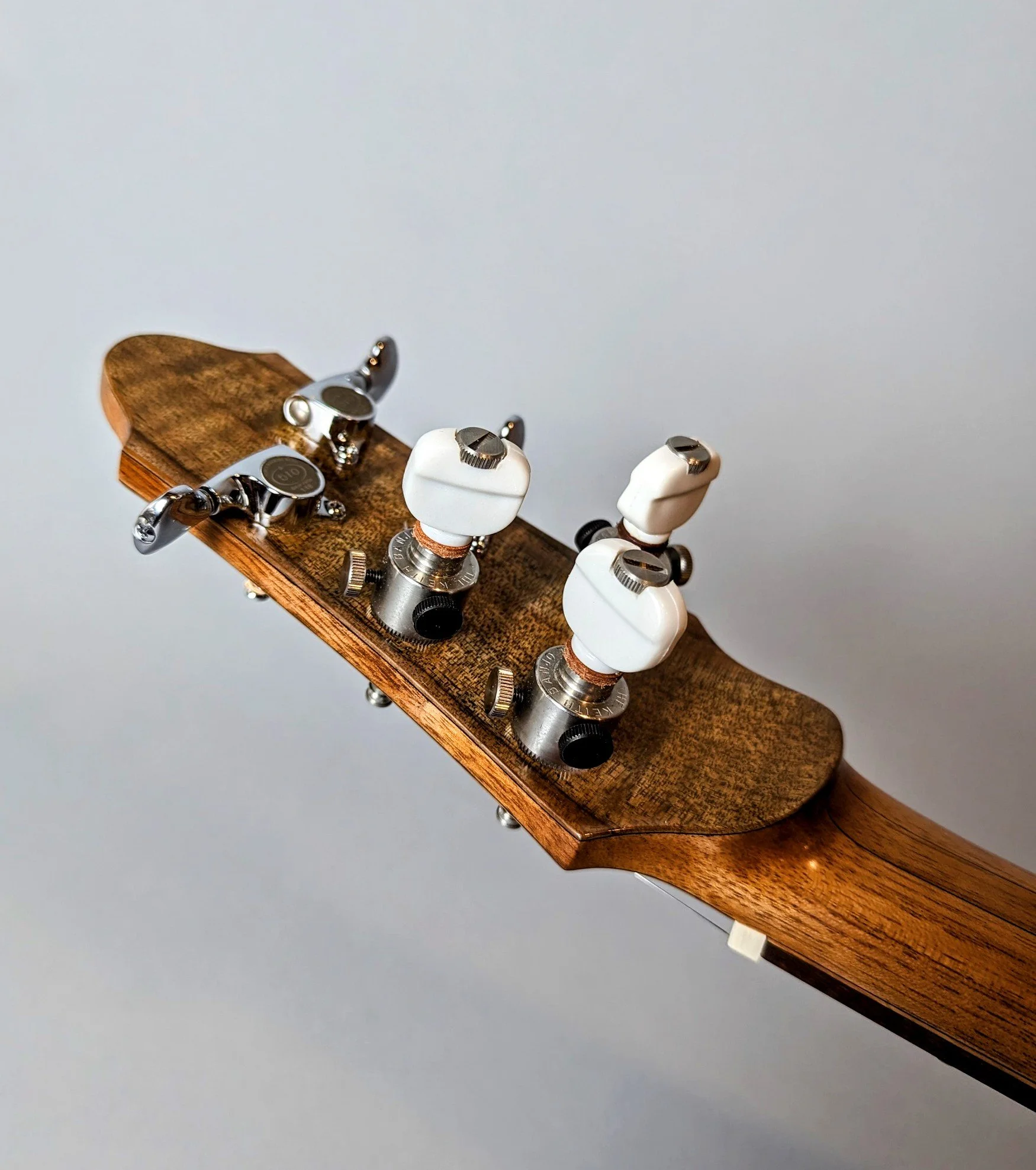 Close-up of a Morgan Kelsey guitar headstock with tuning pegs and white tuning keys.