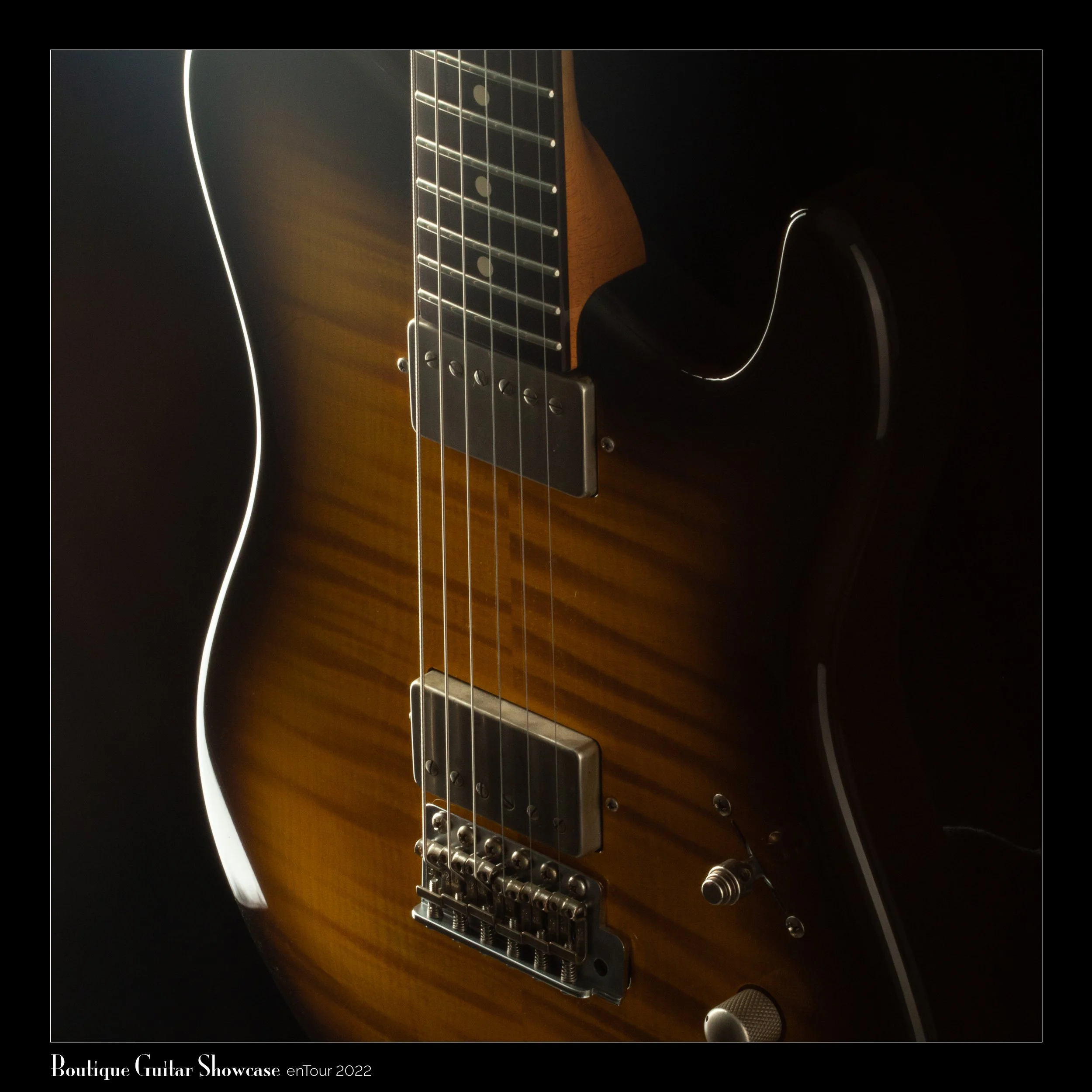 Close-up of a Tausch electric guitar with a sunburst finish, featuring pickups, strings, and a control knob, on a dark background.