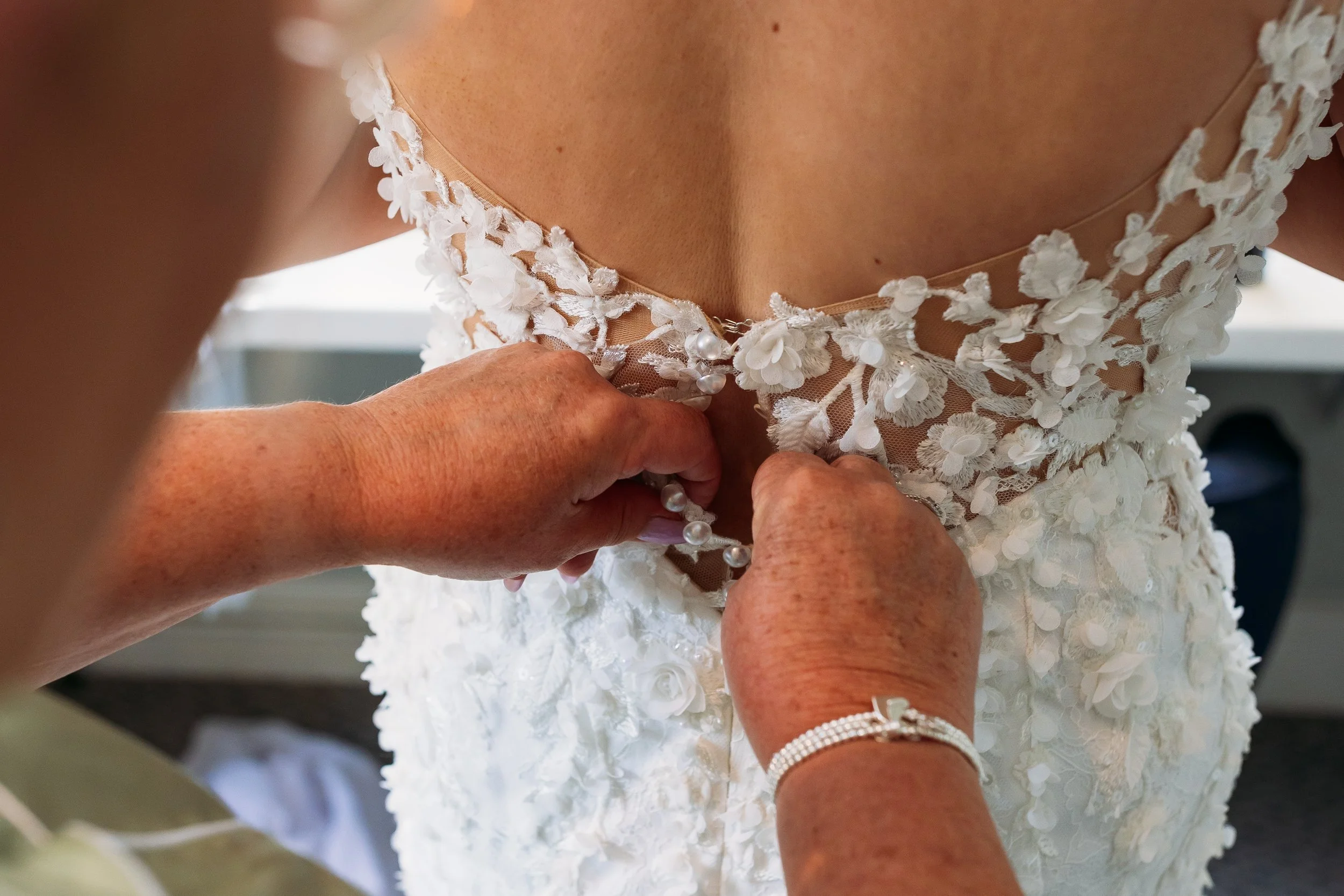 Close-up of bride’s wedding dress being fastened at Combermere Abbey wedding