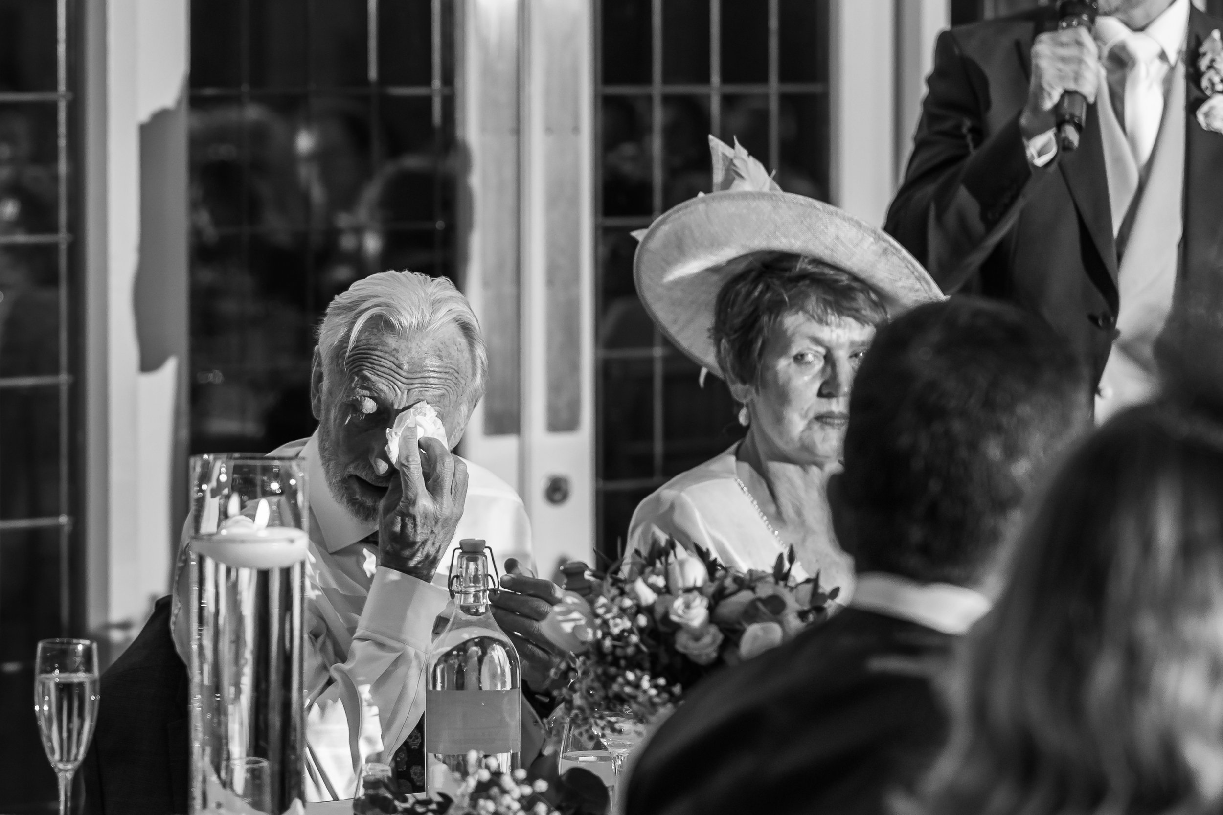 Father of the groom wiping away tears during the wedding speeches while listening to the speaker at Colshaw Hall in Cheshire