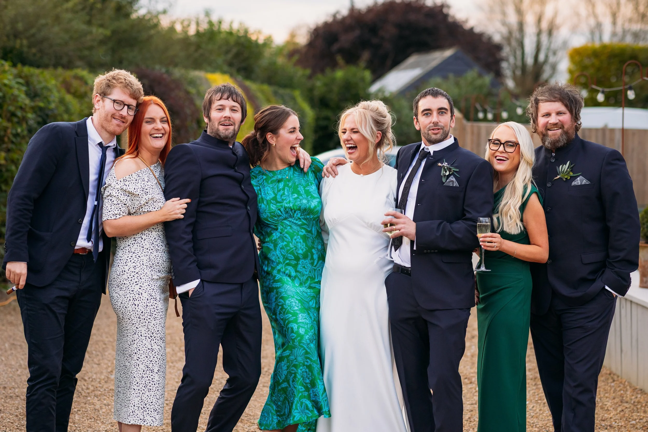 Bride and groom laughing with close friends during a relaxed group photo at Larkspur Lodge wedding drinks reception.