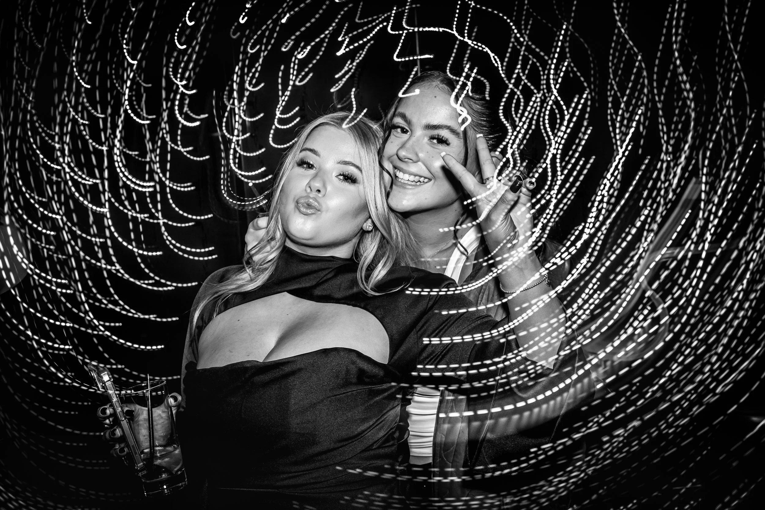 Candid black-and-white party photo of guests posing with light trails at a birthday celebration in Cheshire.