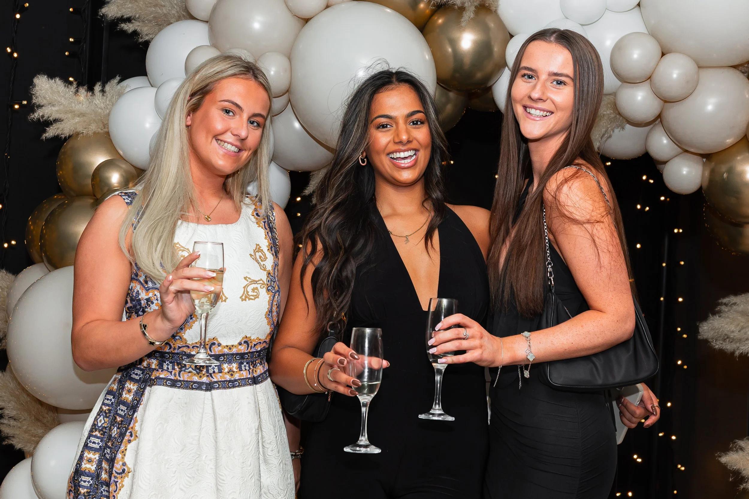 Natural party portrait of guests at a birthday event in Cheshire in front of a ballon backdrop.