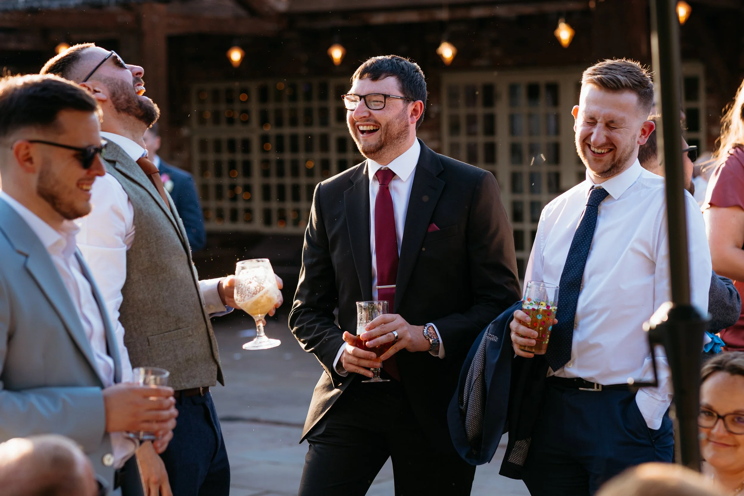 Wedding guests laughing together with drinks during outdoor reception