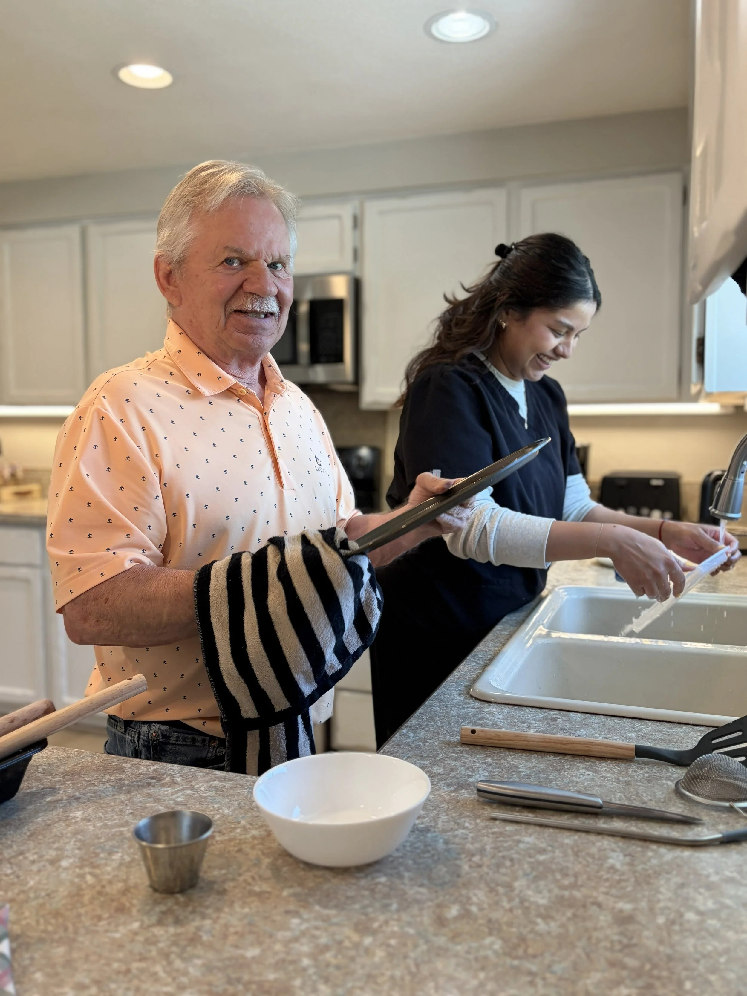 A Belamour Caregiver chopping a vegetable in a kitchen with wooden cabinets, decorated with autumn-themed garland and candles for the elderly memory care patients in Vancouver Washington.