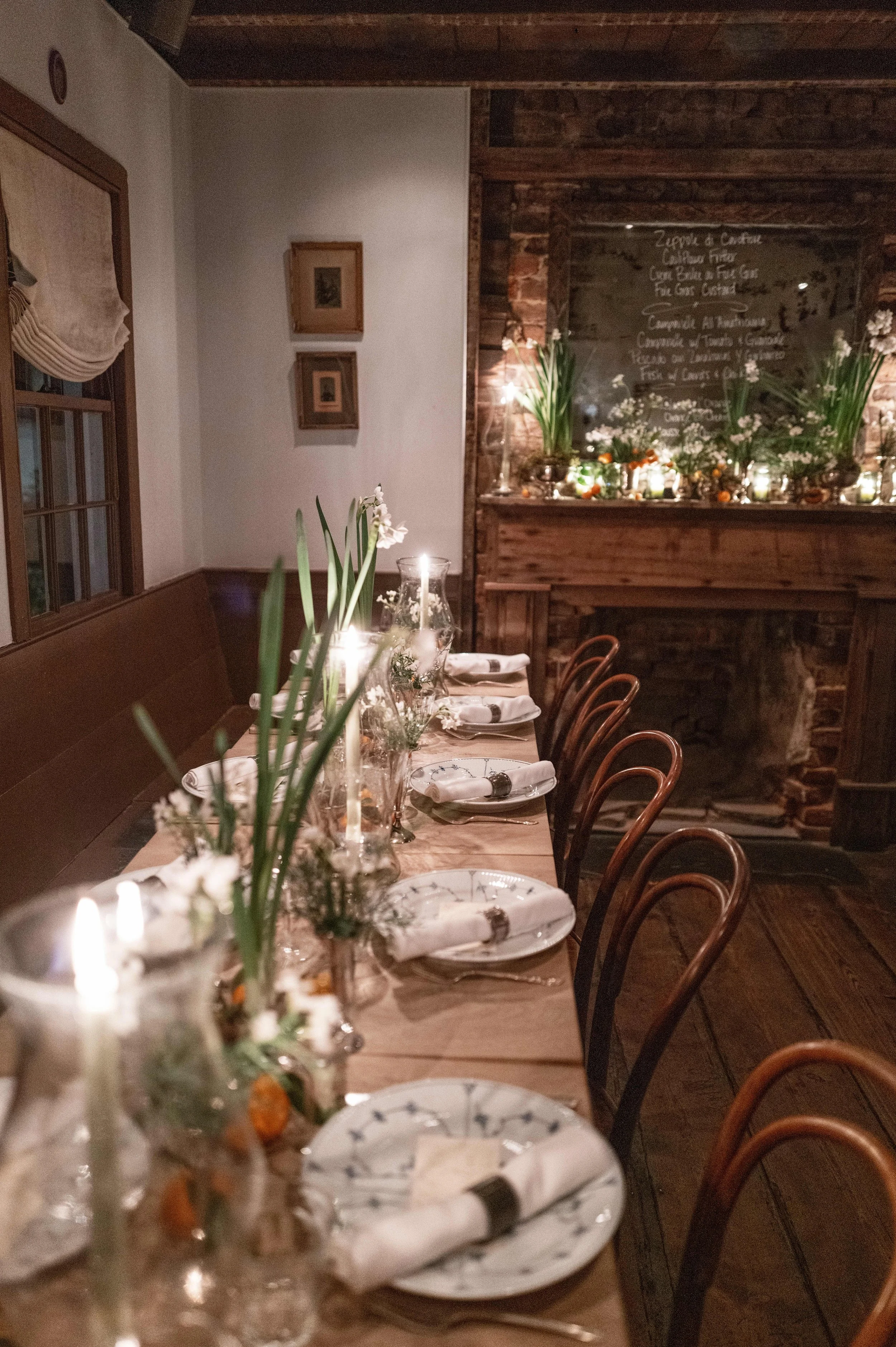 Etched Hurricane glass centerpiece with candles on dining table with flowers.