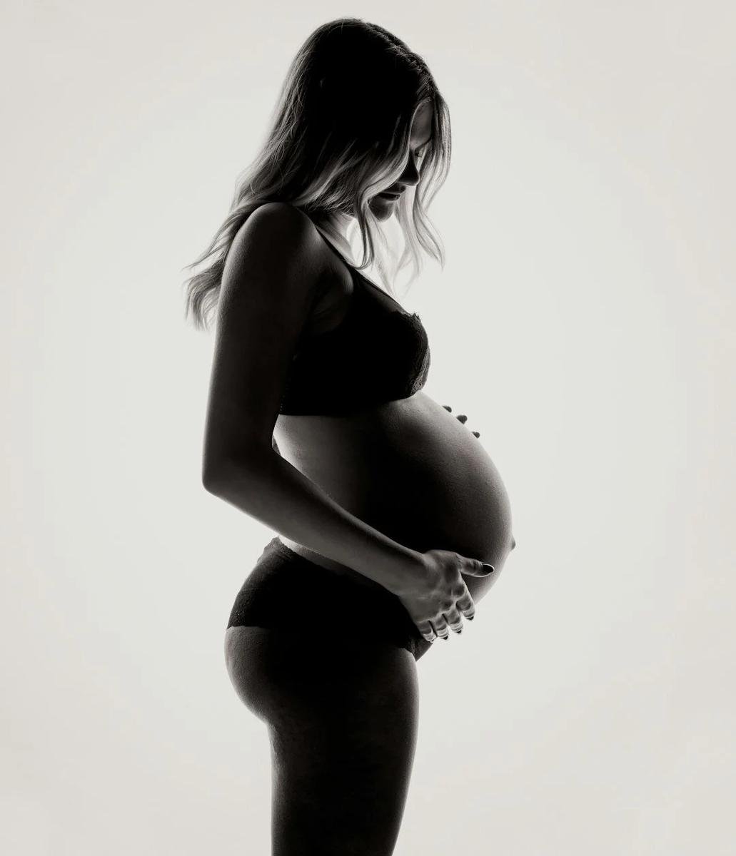 Black-and-white silhouette of a pregnant woman in profile cradling her belly — Webster Technique prenatal chiropractor in Solana Beach