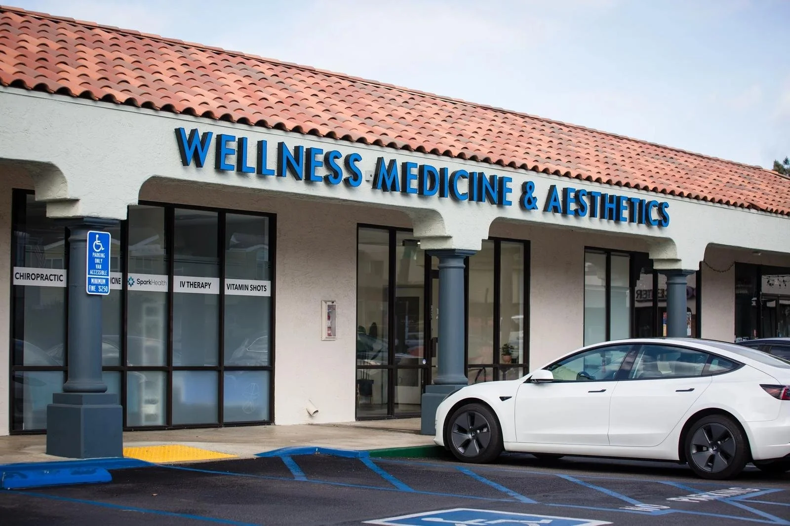 Wellness Medicine & Aesthetics storefront sign on Lomas Santa Fe Drive in Solana Beach, with chiropractic signage and a white Tesla parked — chiropractor in Solana Beach CA