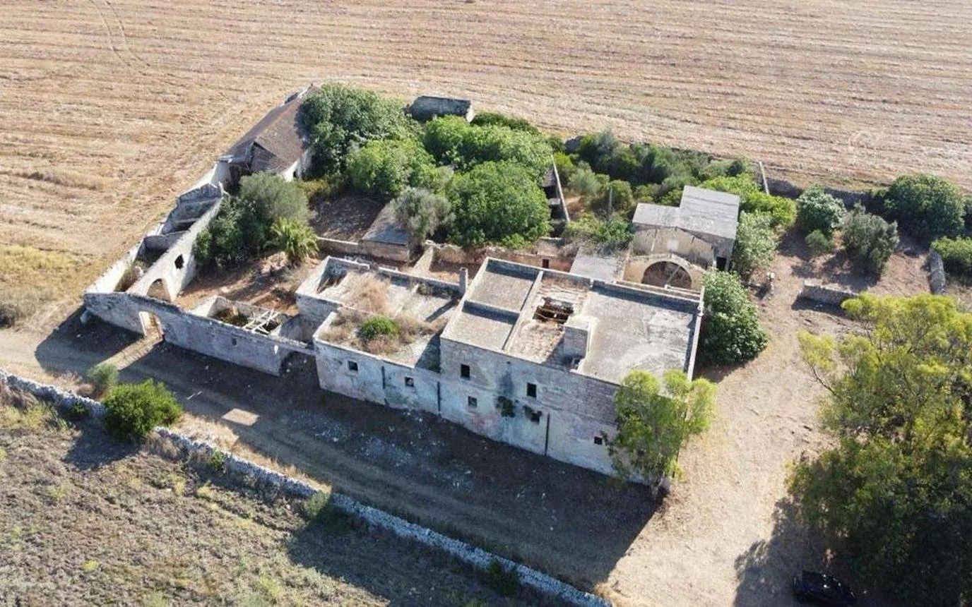 Traditional Puglian masseria with courtyard, white stone walls, olive trees, and restored interior