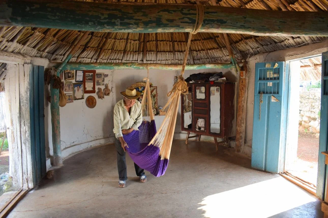 Traditional Mayan house with palm and wood, hammock interior, and natural ventilation
