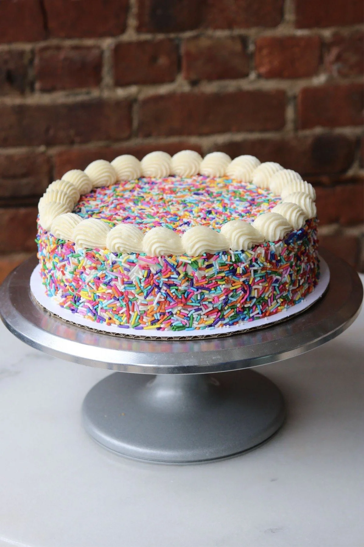An image of a vanilla birthday cake with vanilla buttercream frosting and sprinkles from The Good Batch Bakery in Brooklyn, NYC