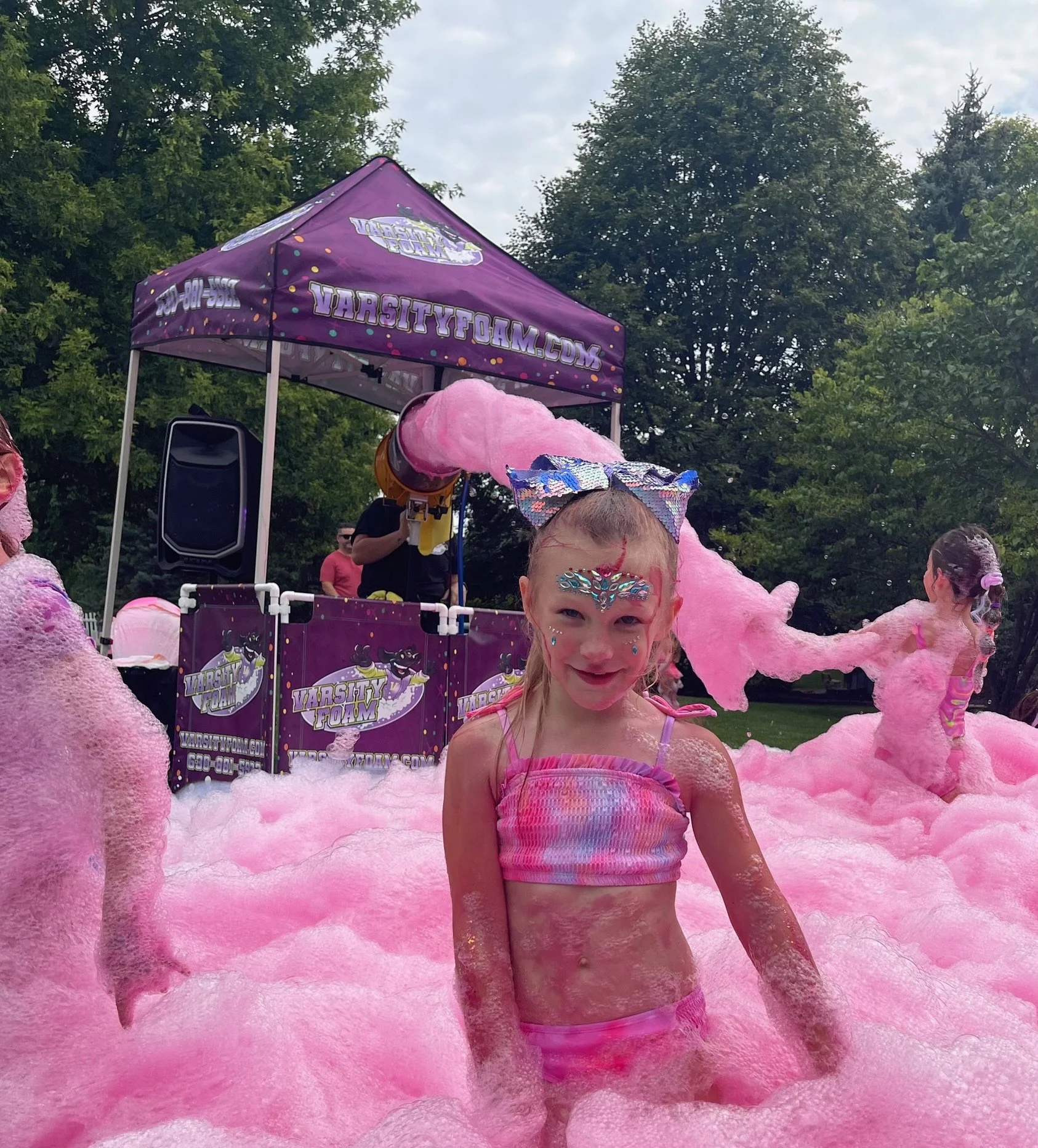 Woman enjoying a Varsity Foam pink foam party in Chicagoland at an outdoor event with pink colored foam
