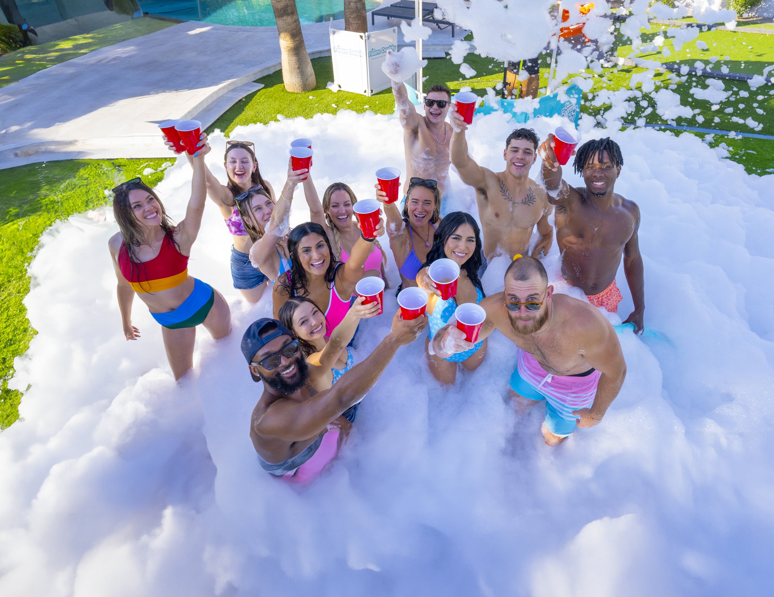 Group of young adults enjoying a Varsity Foam foam party in Chicagoland with foam covering the ground at an outdoor event