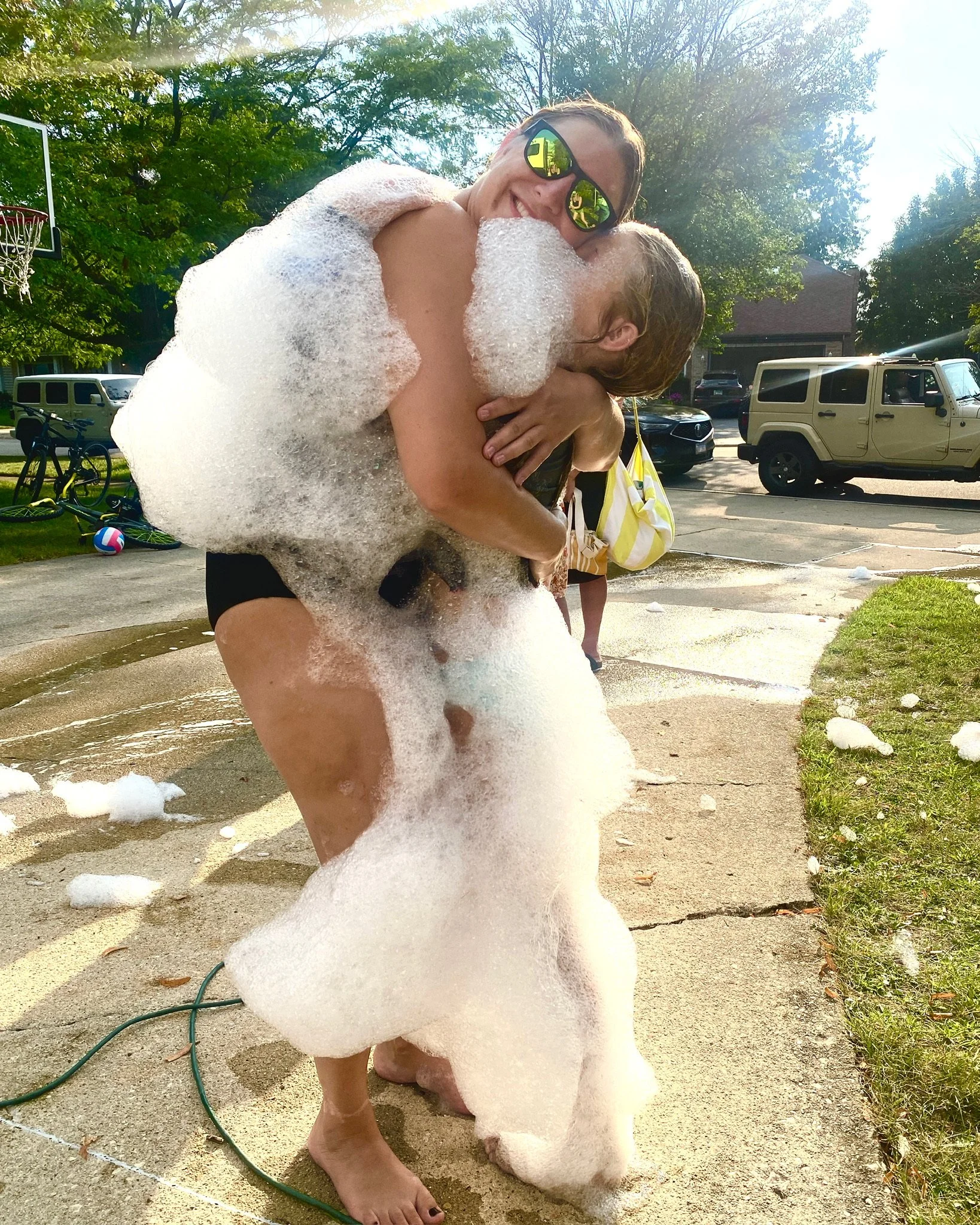 Woman covered in foam at a Varsity Foam party in Chicagoland being lifted in celebration at an outdoor event