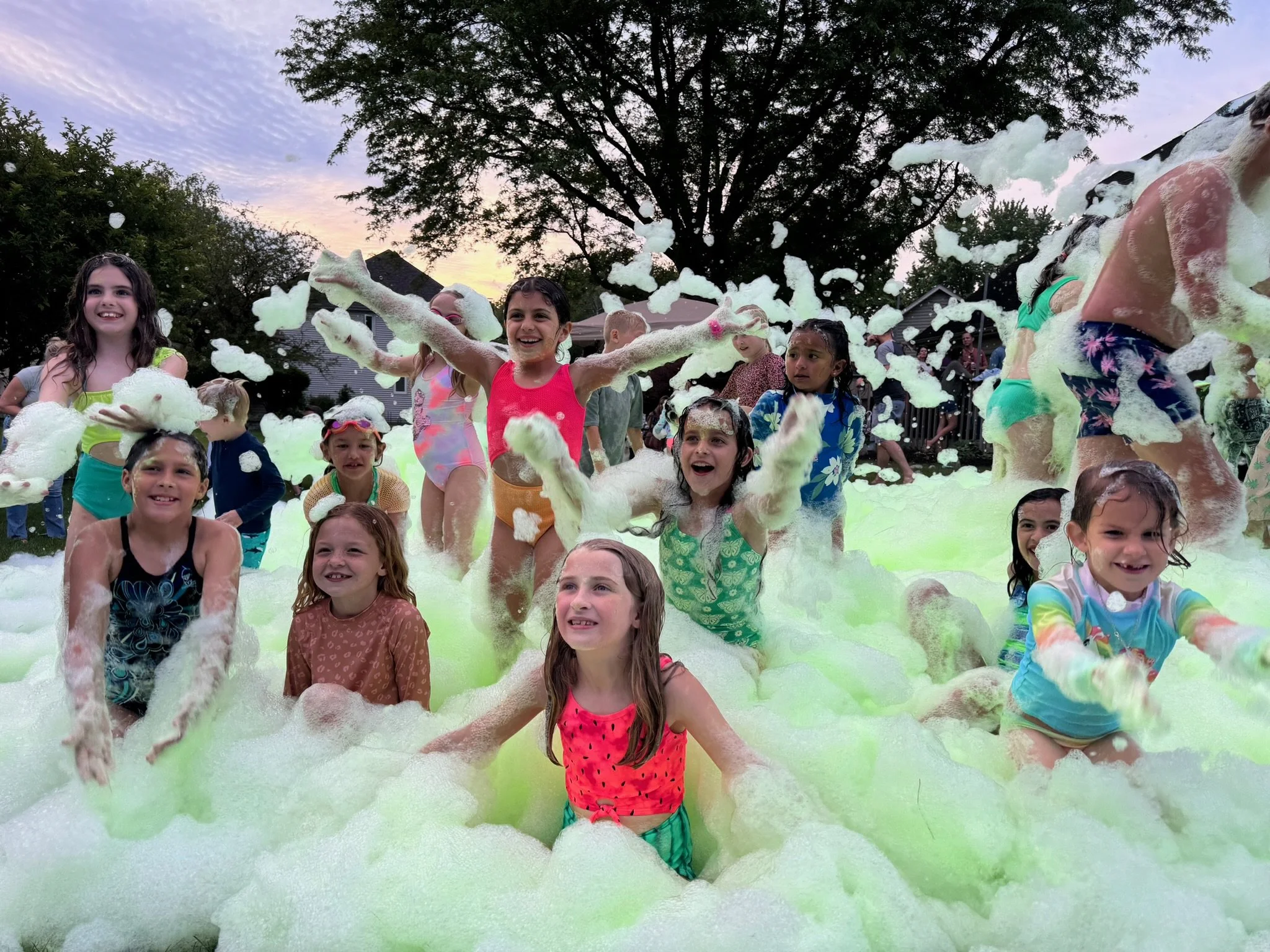 Kids celebrating at a Varsity Foam foam party in Chicagoland, throwing foam in the air at an outdoor event