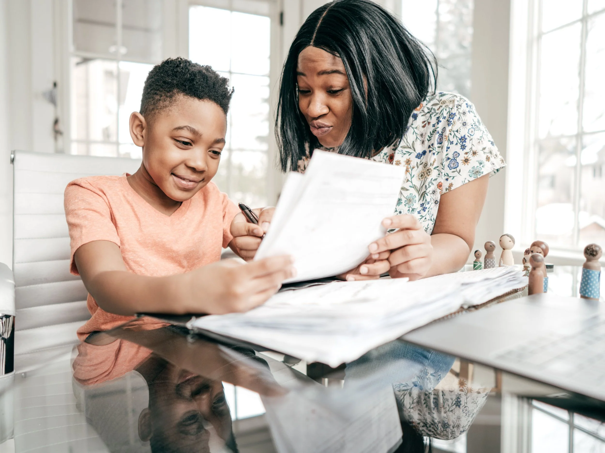 black mom and son at the dining table doing schoolwork doing