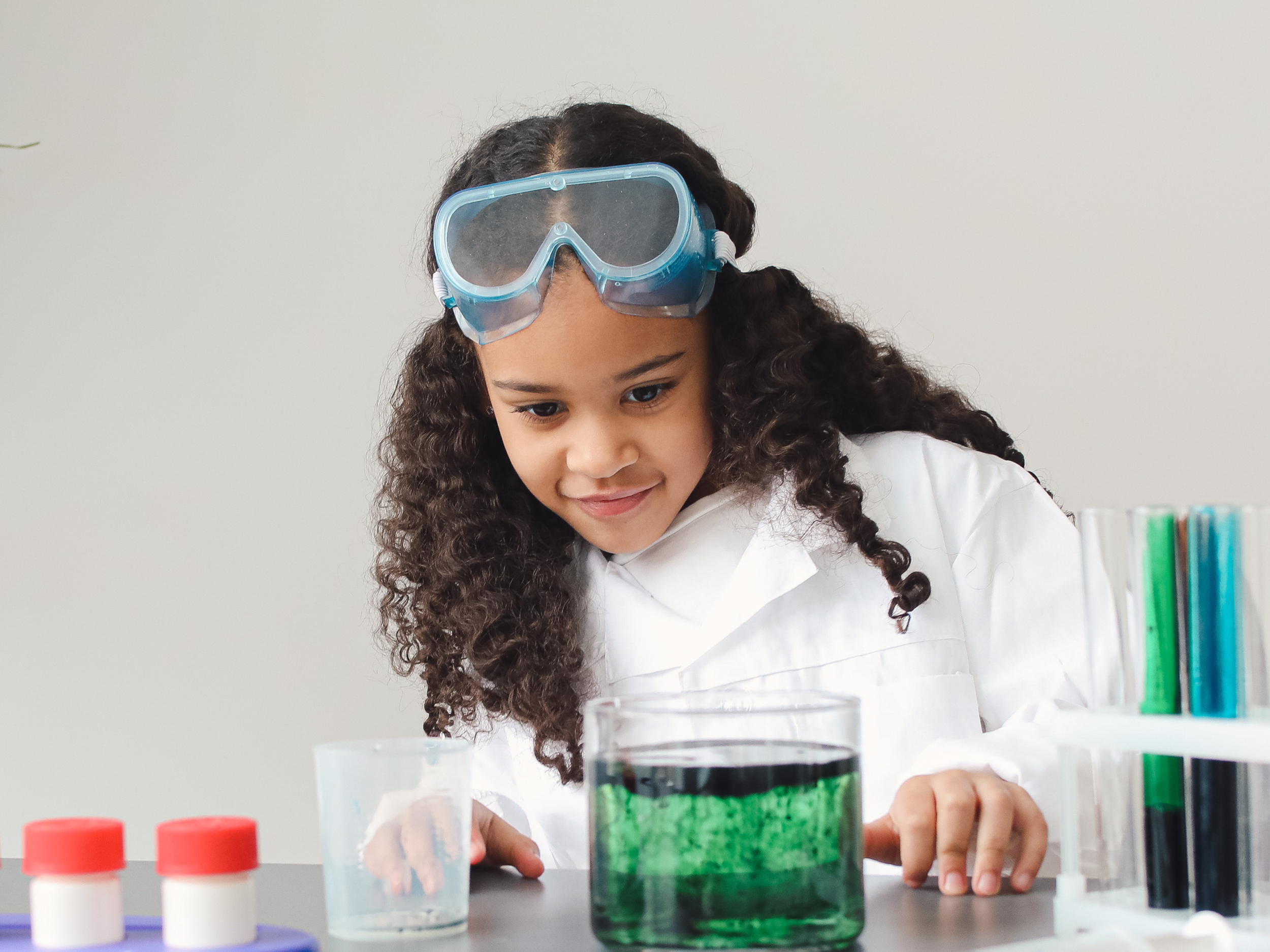 young black girl wearing science gear and doing a science experiment
