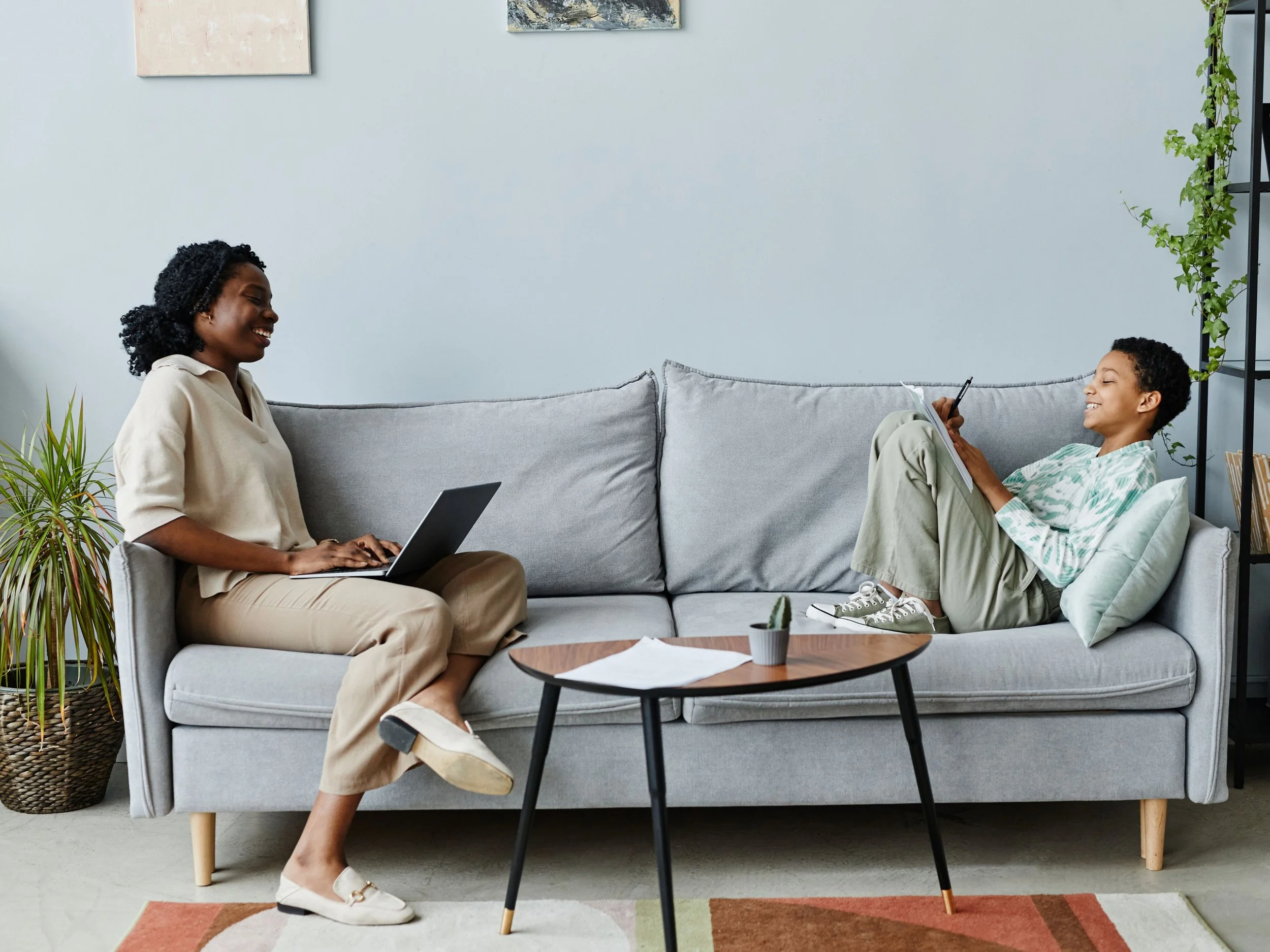 black mom and dad sitting on couch laughing and chatting while working