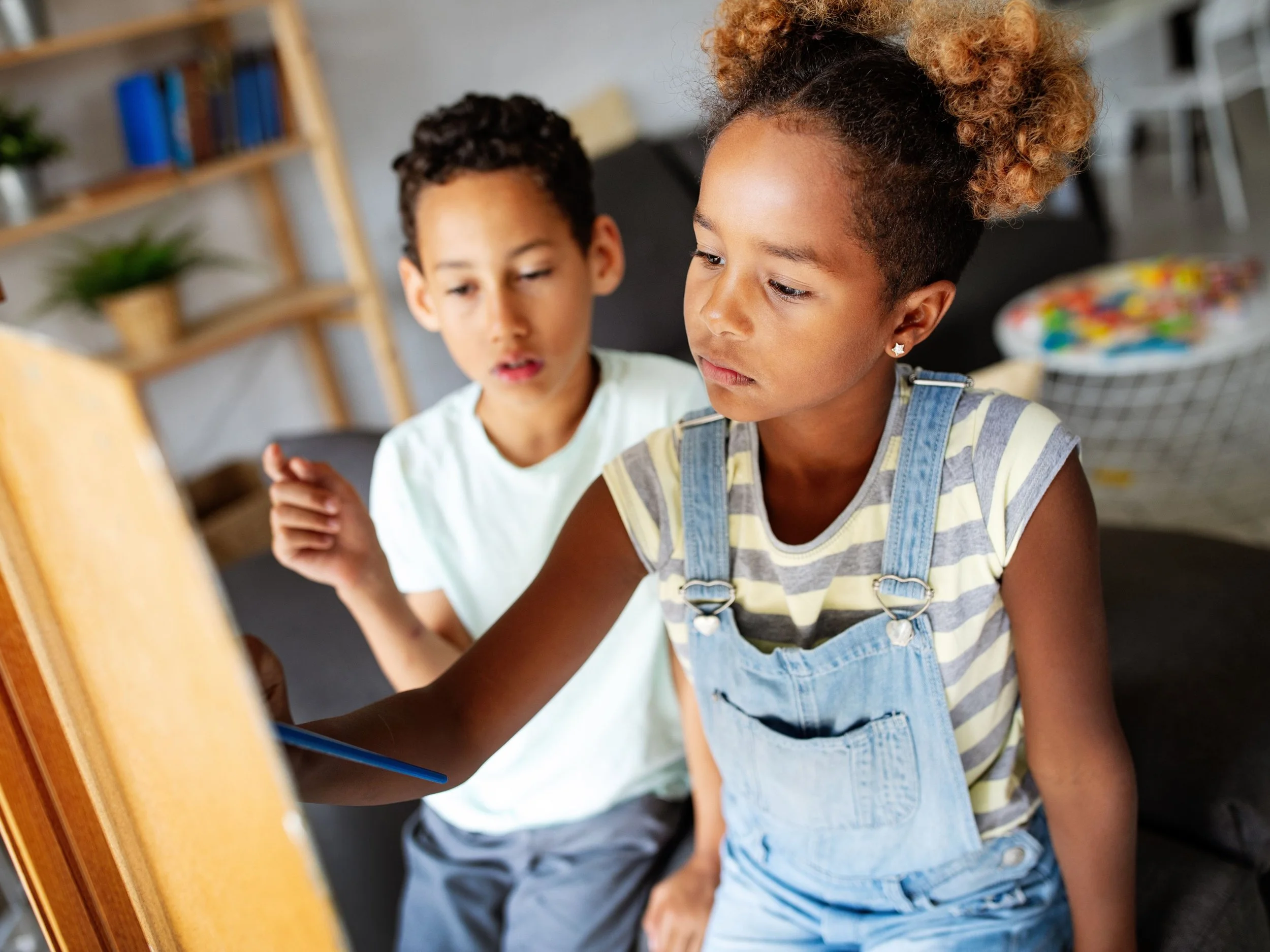 young black boy and girl painting on a canvas
