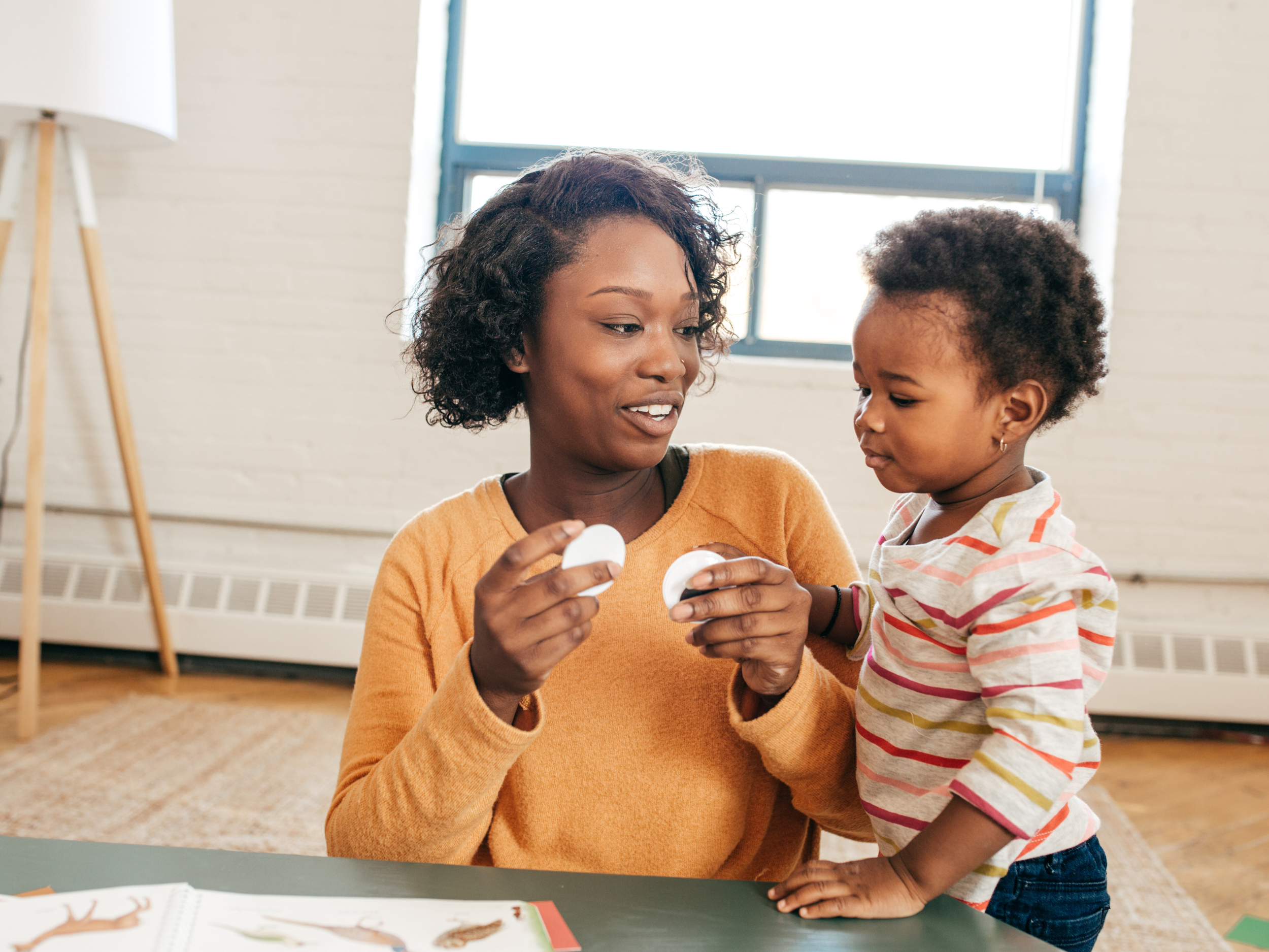black mom at table teaching toddler girl