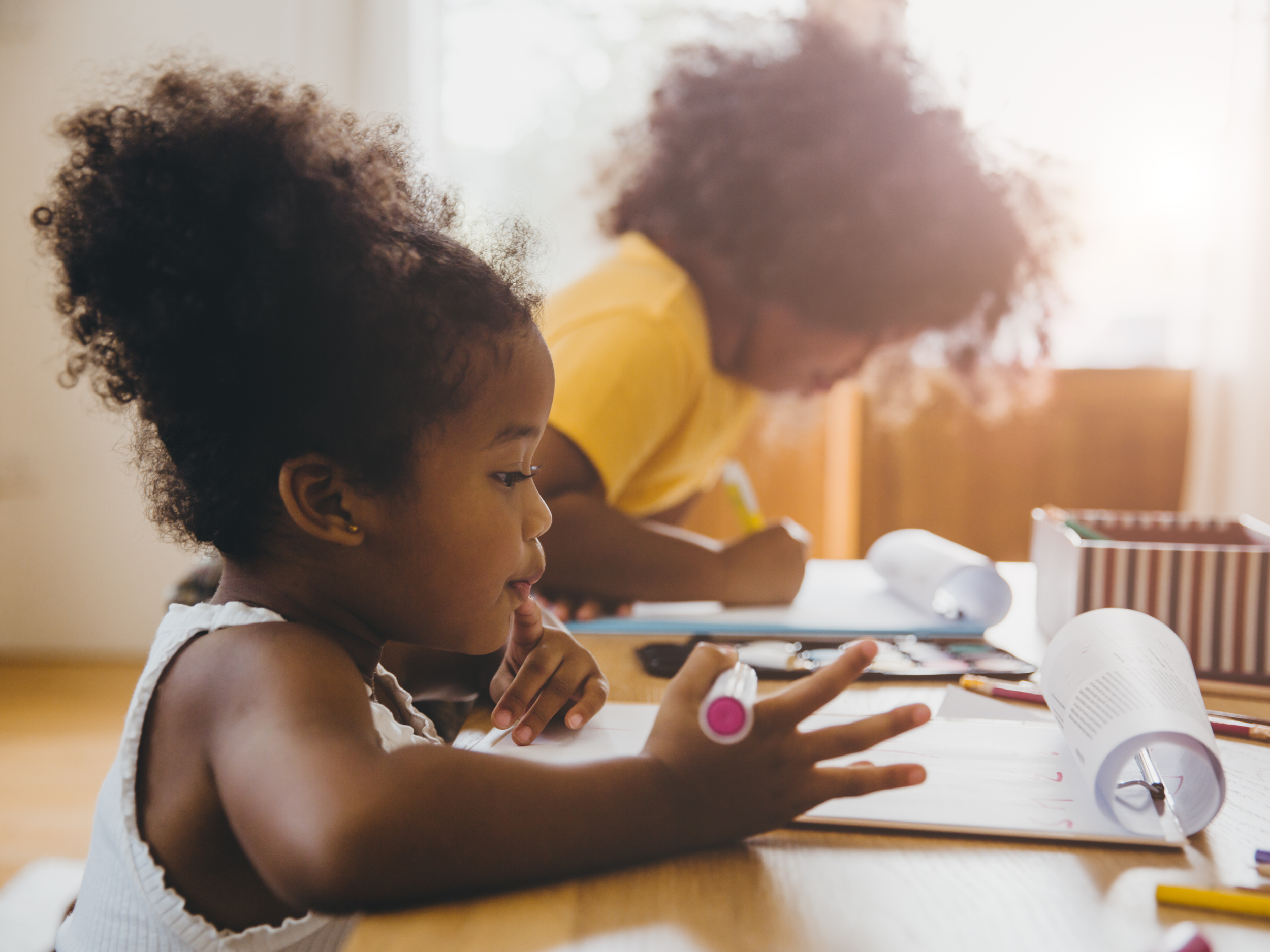 two little black girls sitting at table doing schoolwork