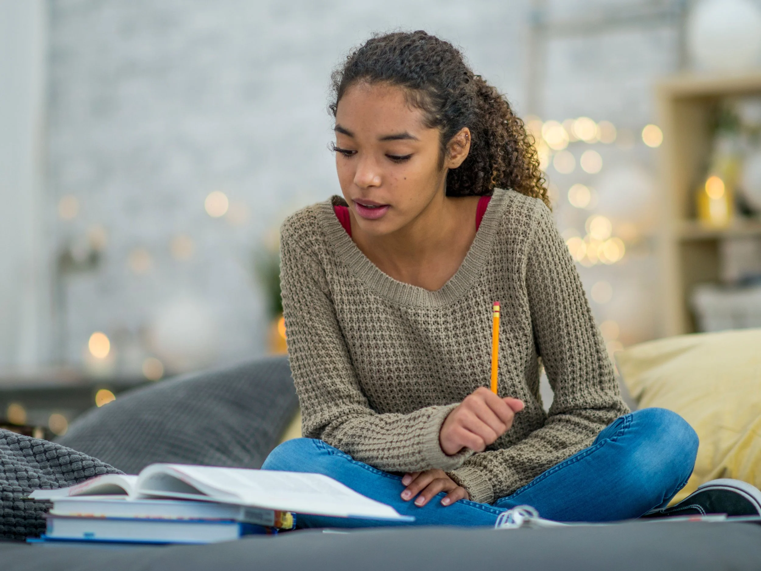 young black girl sitting on couch doing schoolwork