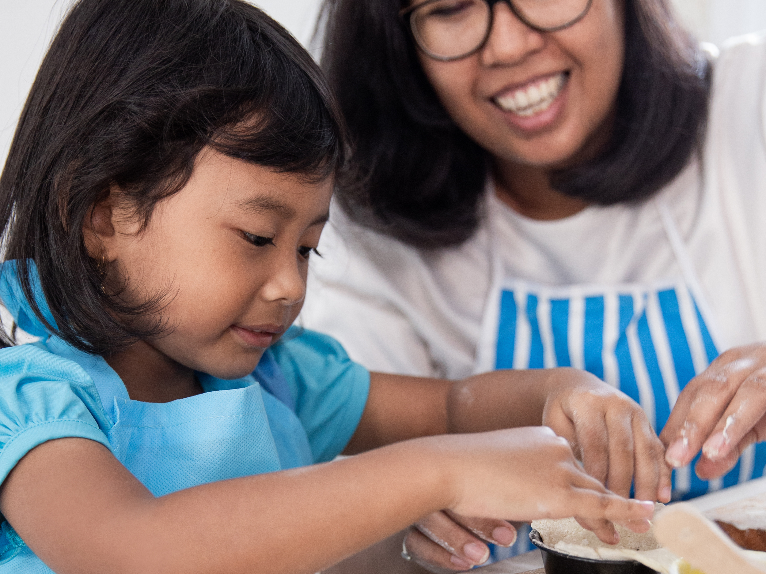 closeup of mom teaching daughter to bake