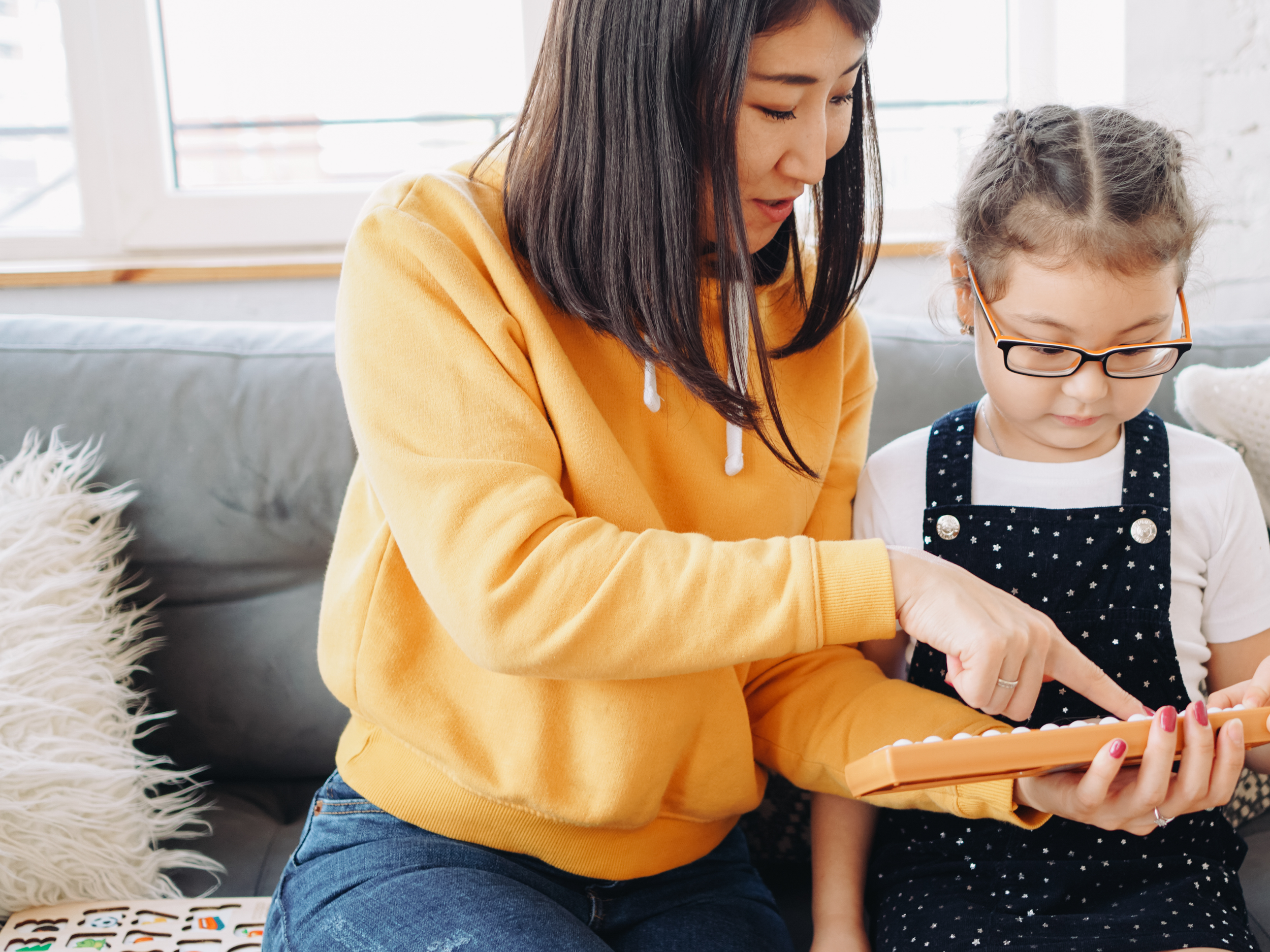 mom sitting on couch helping daughter with school work