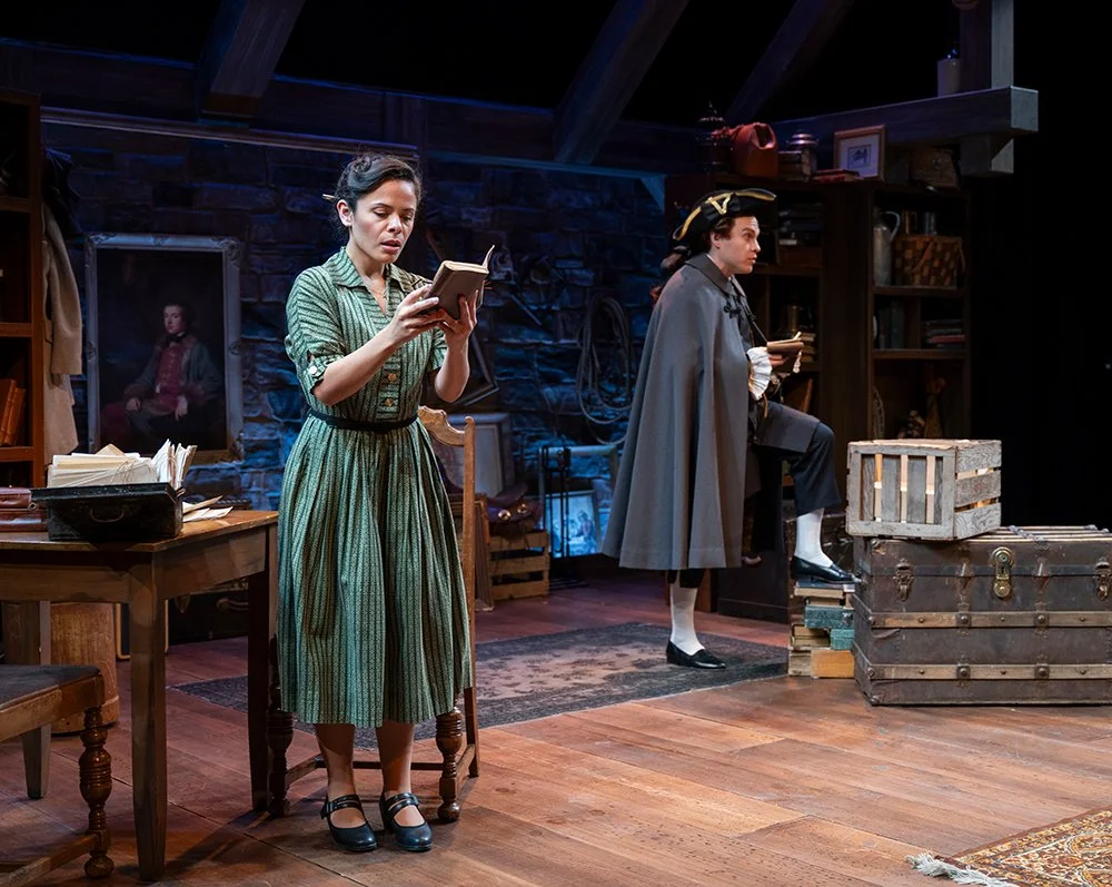 Joan reading a journal while Boswell acts it out in the background