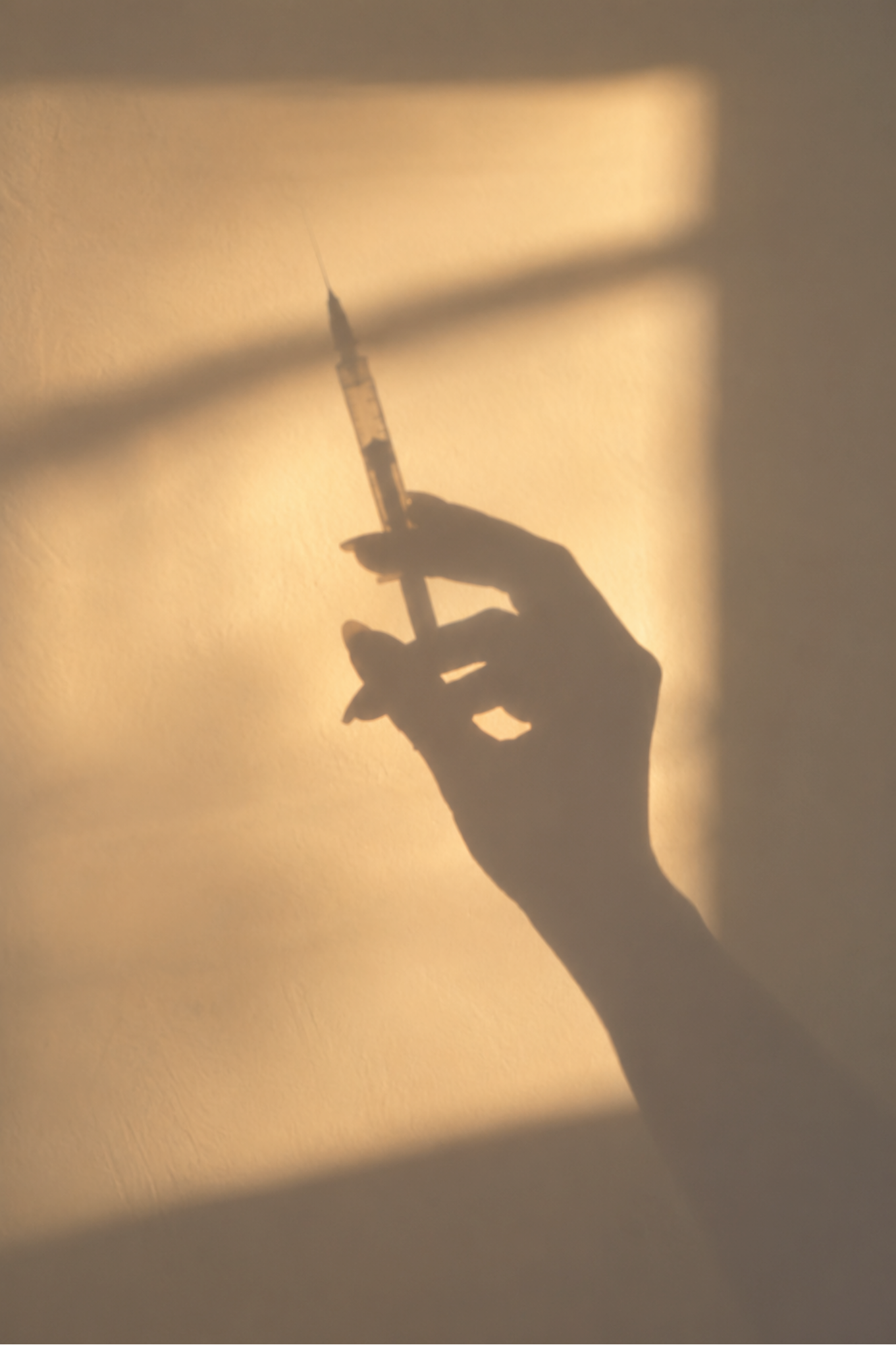 Silhouette of an injector's hand holding a syringe in warm golden light, for the Golden Hour Botox and facial package at Skinship