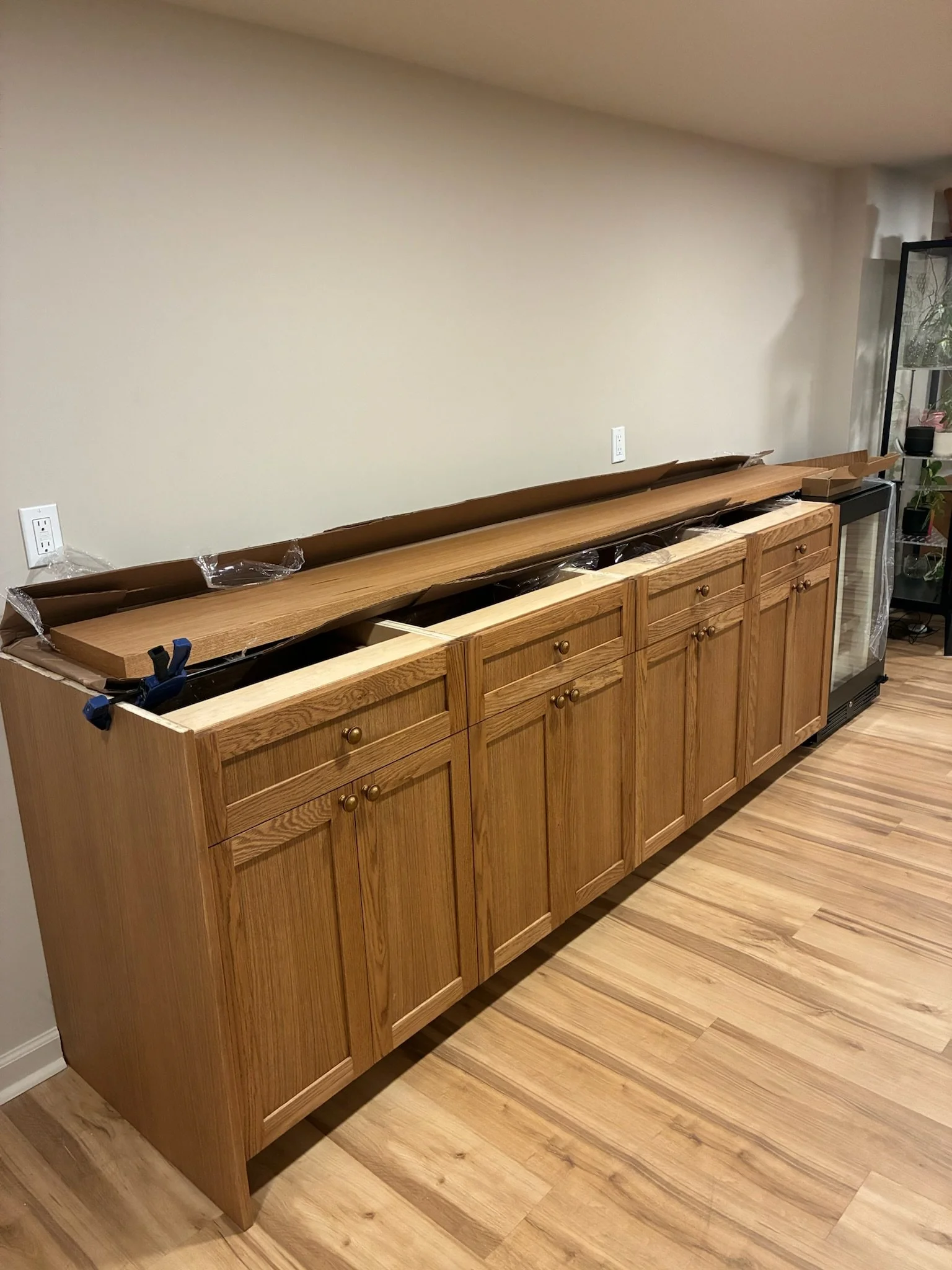 Wooden kitchen cabinets with a countertop lying on top, waiting for installation, in a room with hardwood floors.