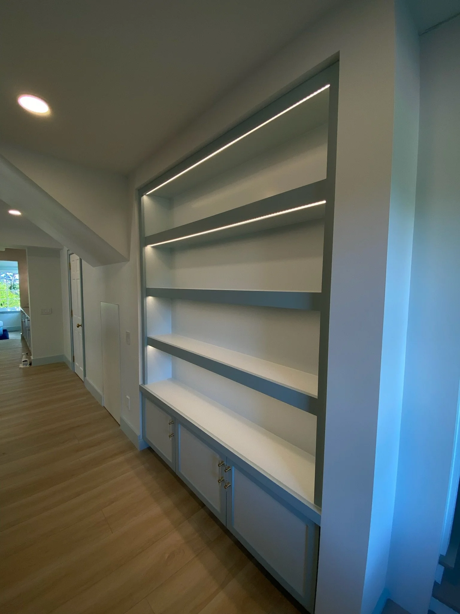 White built-in shelving unit with state-of-the-art lighting in a modern home interior.