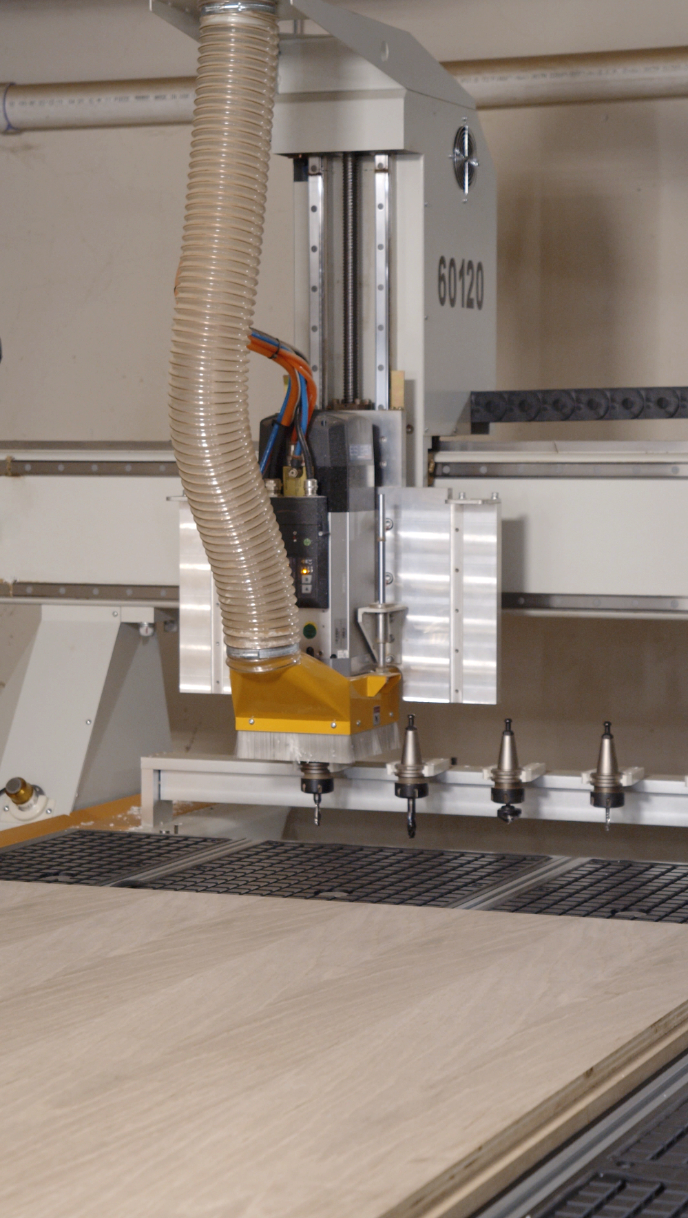Industrial CNC router machine cutting wood panel in a workshop.