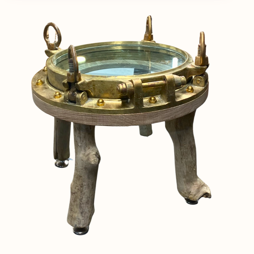 A vintage maritime ship's deck compass with brass components, glass cover, and wooden legs.